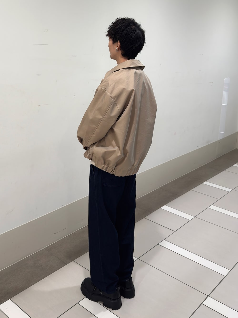 ベージュ系のブルゾン、グレー系のスウェット、ブルー系のデニムパンツを着用したメンズの春コーディネートの2枚目の写真