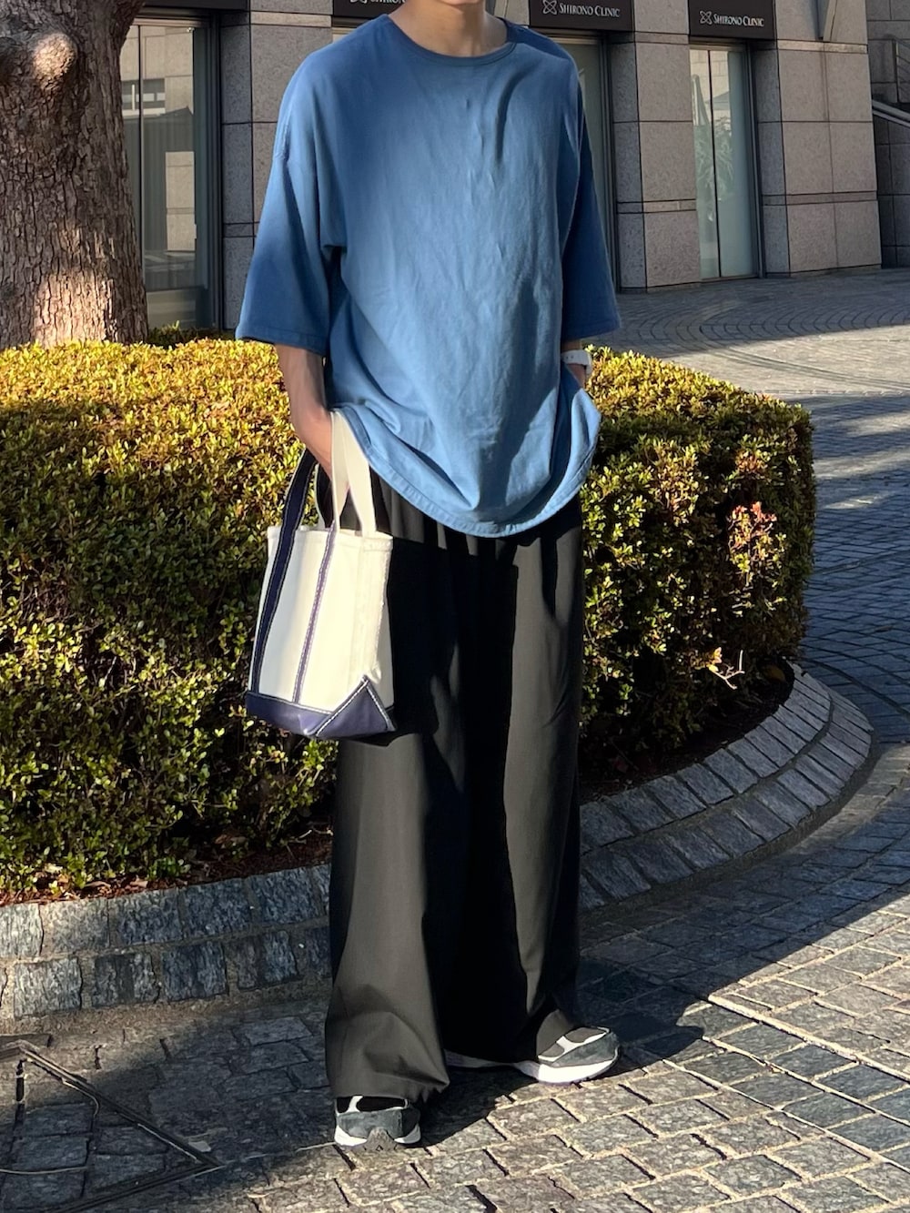 ブルー系のTシャツ/カットソー、ブラック系のスラックス、ブラック系のスニーカーを着用したメンズの夏コーディネートの2枚目の写真
