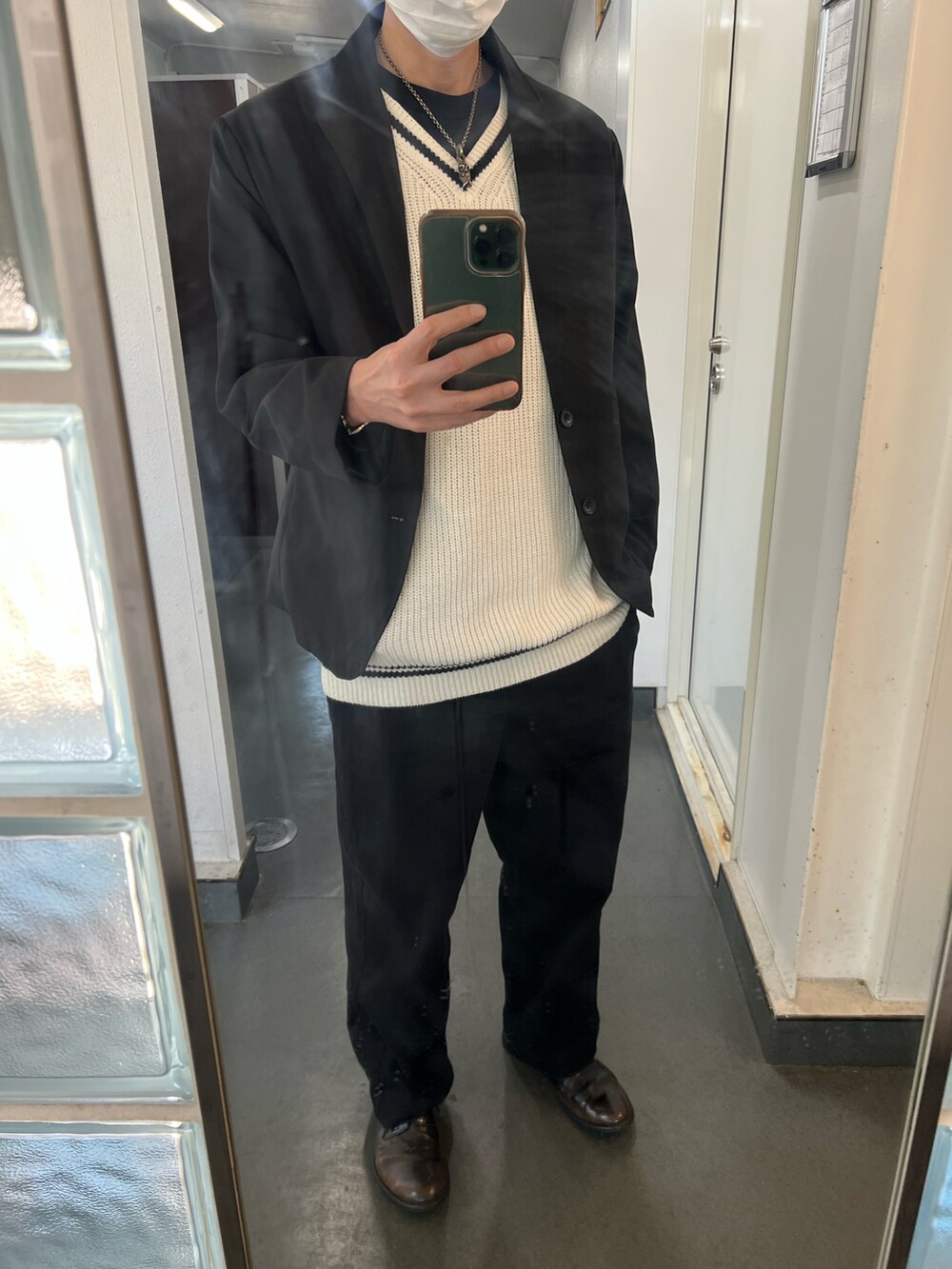 ブラック系のテーラードジャケット、ブラック系のチノパンツ、ホワイト系のニット/セーターを着用したメンズの秋コーディネートの3枚目の写真