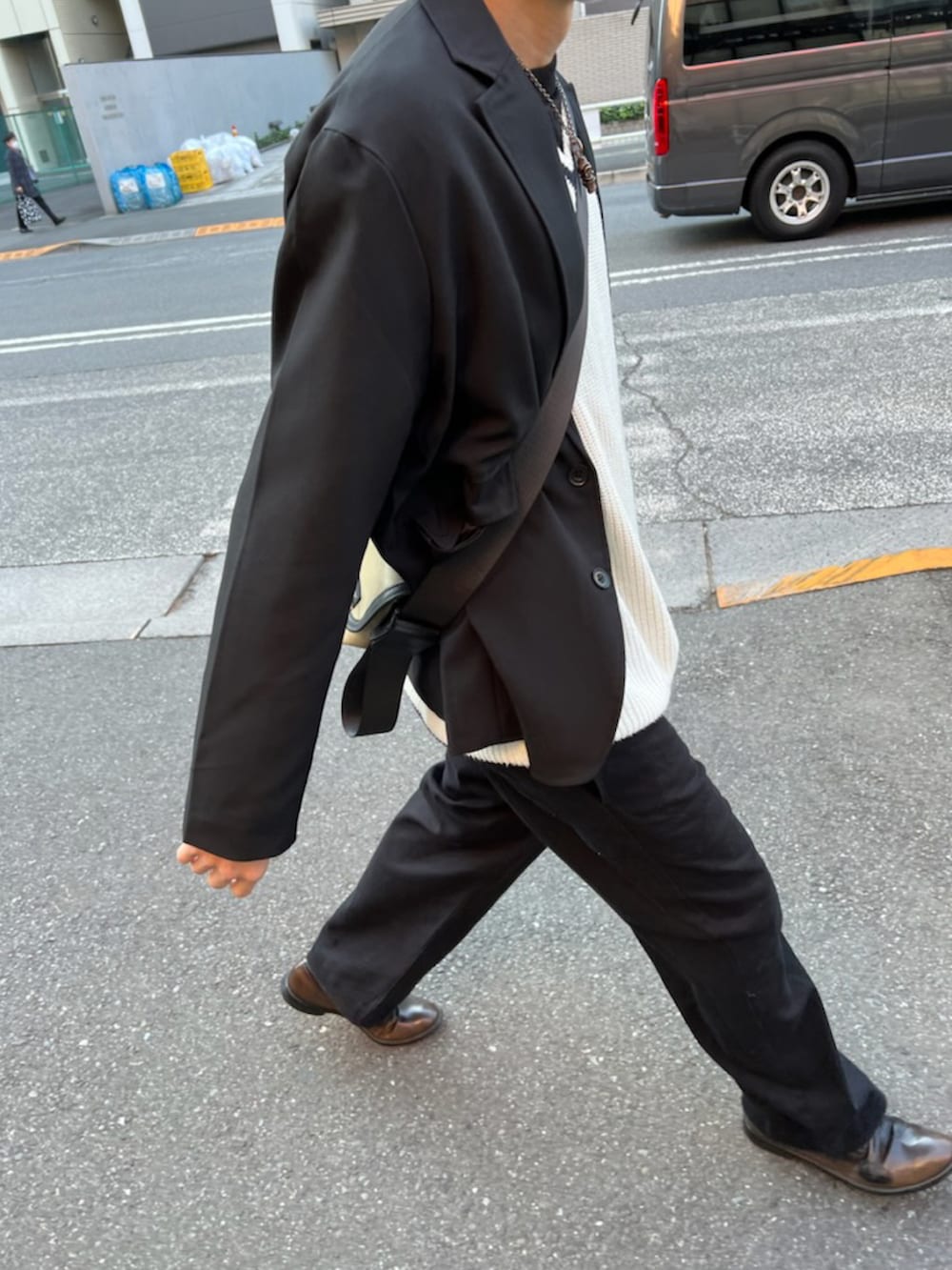 ブラック系のテーラードジャケット、ブラック系のチノパンツ、ホワイト系のニット/セーターを着用したメンズの秋コーディネートの2枚目の写真