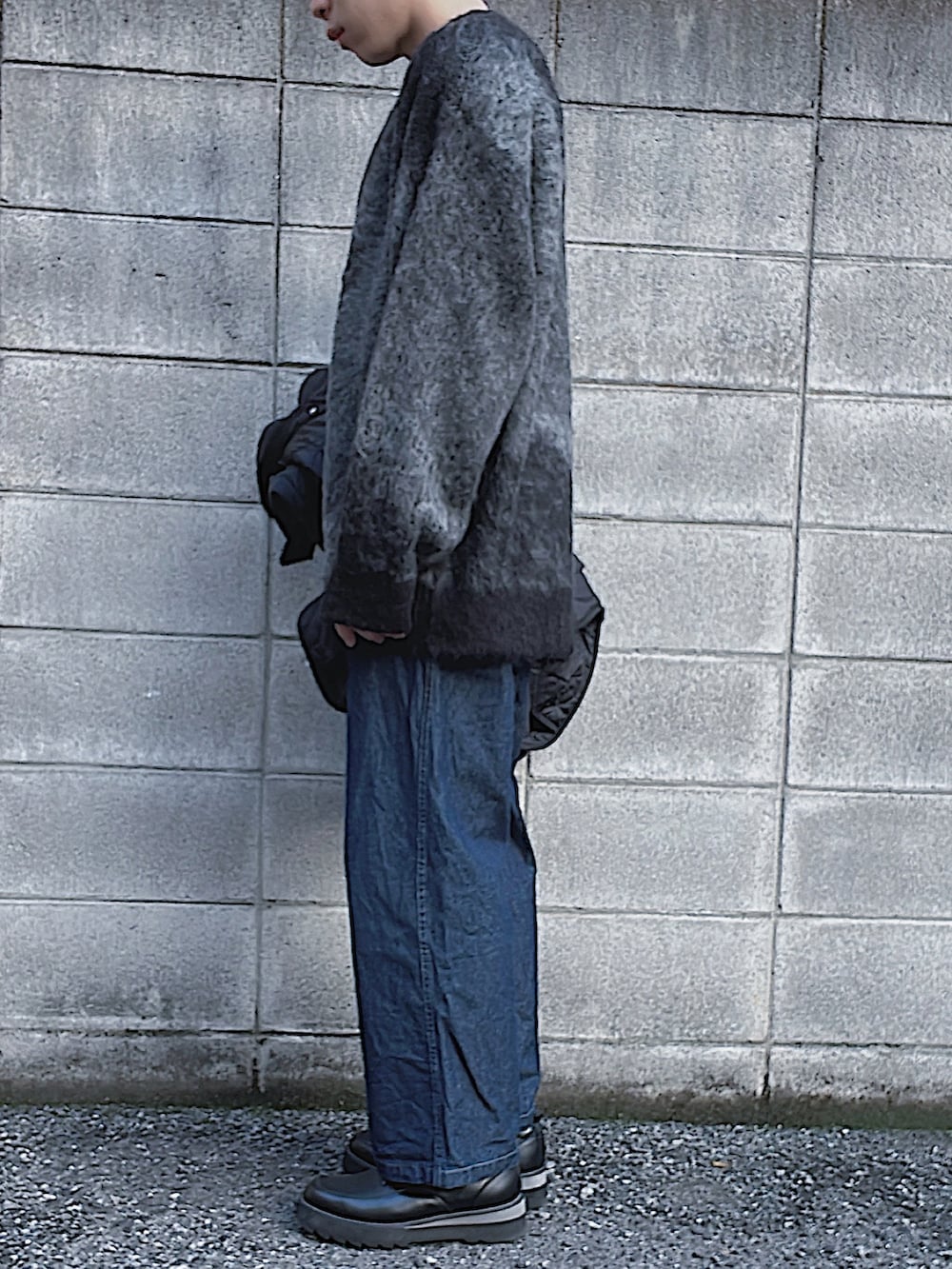 グレー系のニット/セーター、ブルー系のデニムパンツ、ブラック系のドレスシューズを着用したメンズの冬コーディネートの2枚目の写真