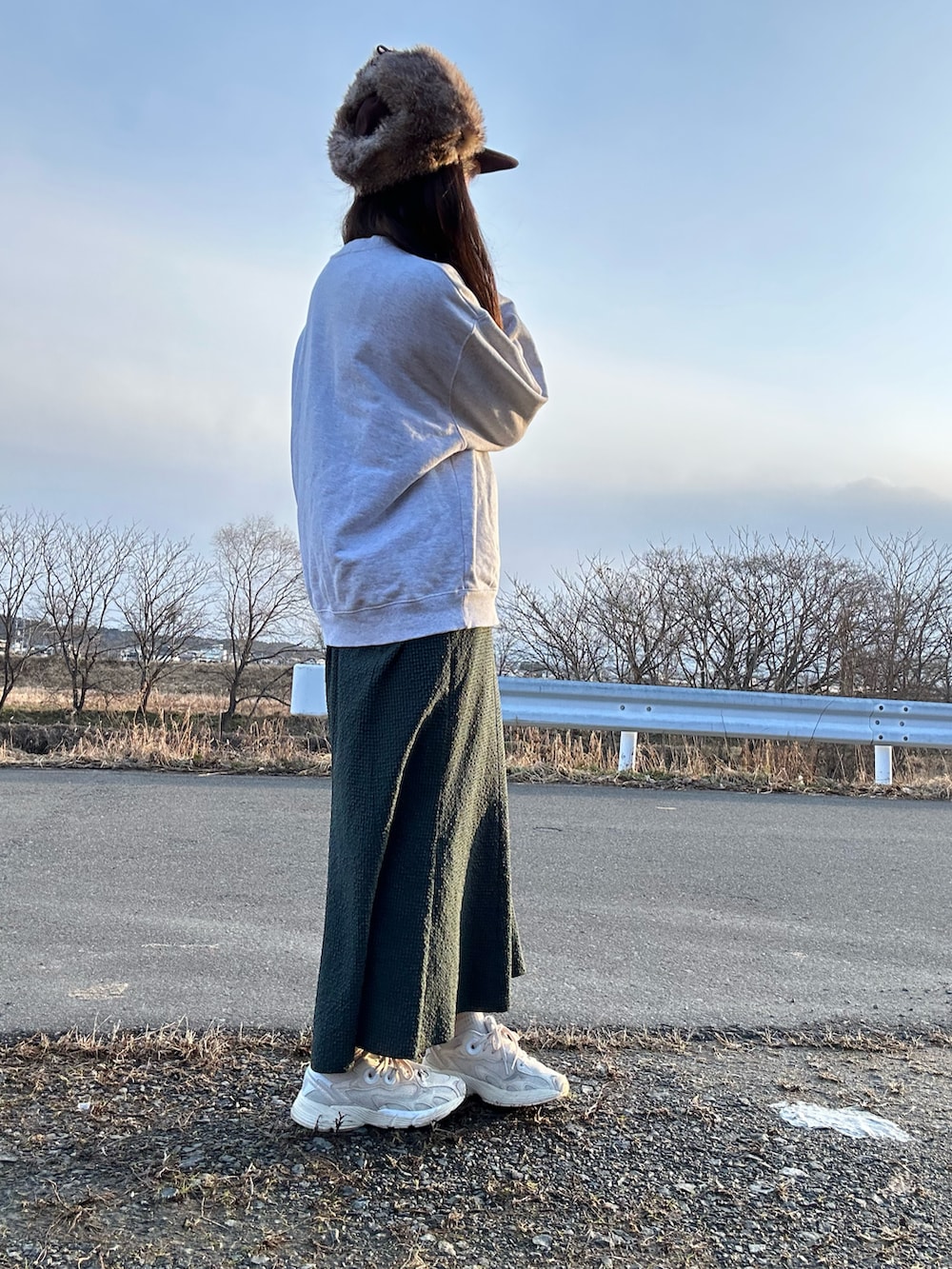 グレー系のスウェット、グリーン系のワンピース、ホワイト系のスニーカーを着用したレディースの冬コーディネートの2枚目の写真