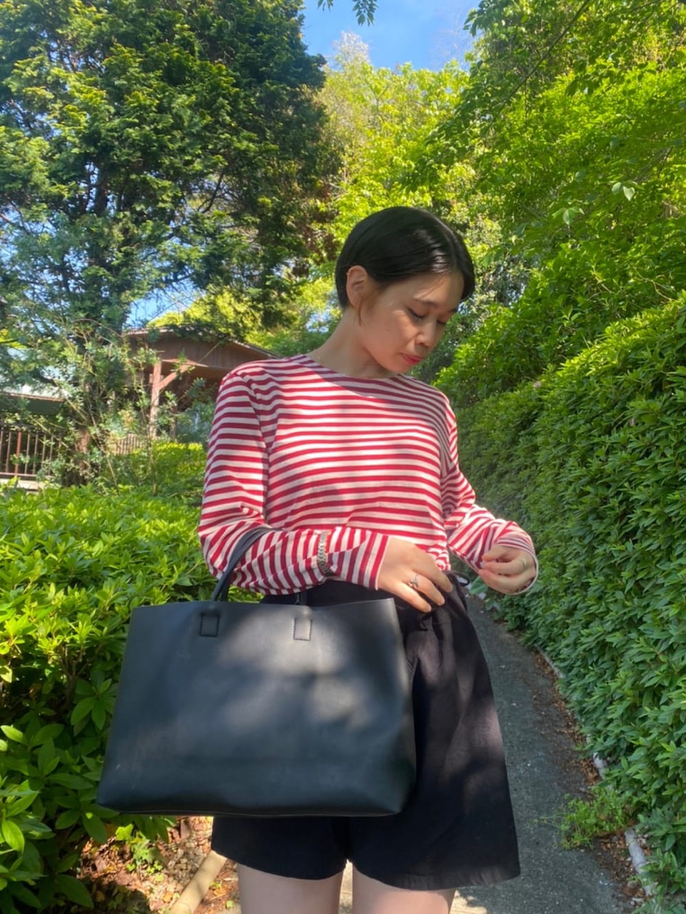 レッド系のTシャツ/カットソー、ブラック系のパンツ、ブラック系のトートバッグを着用したレディースの春コーディネートの2枚目の写真