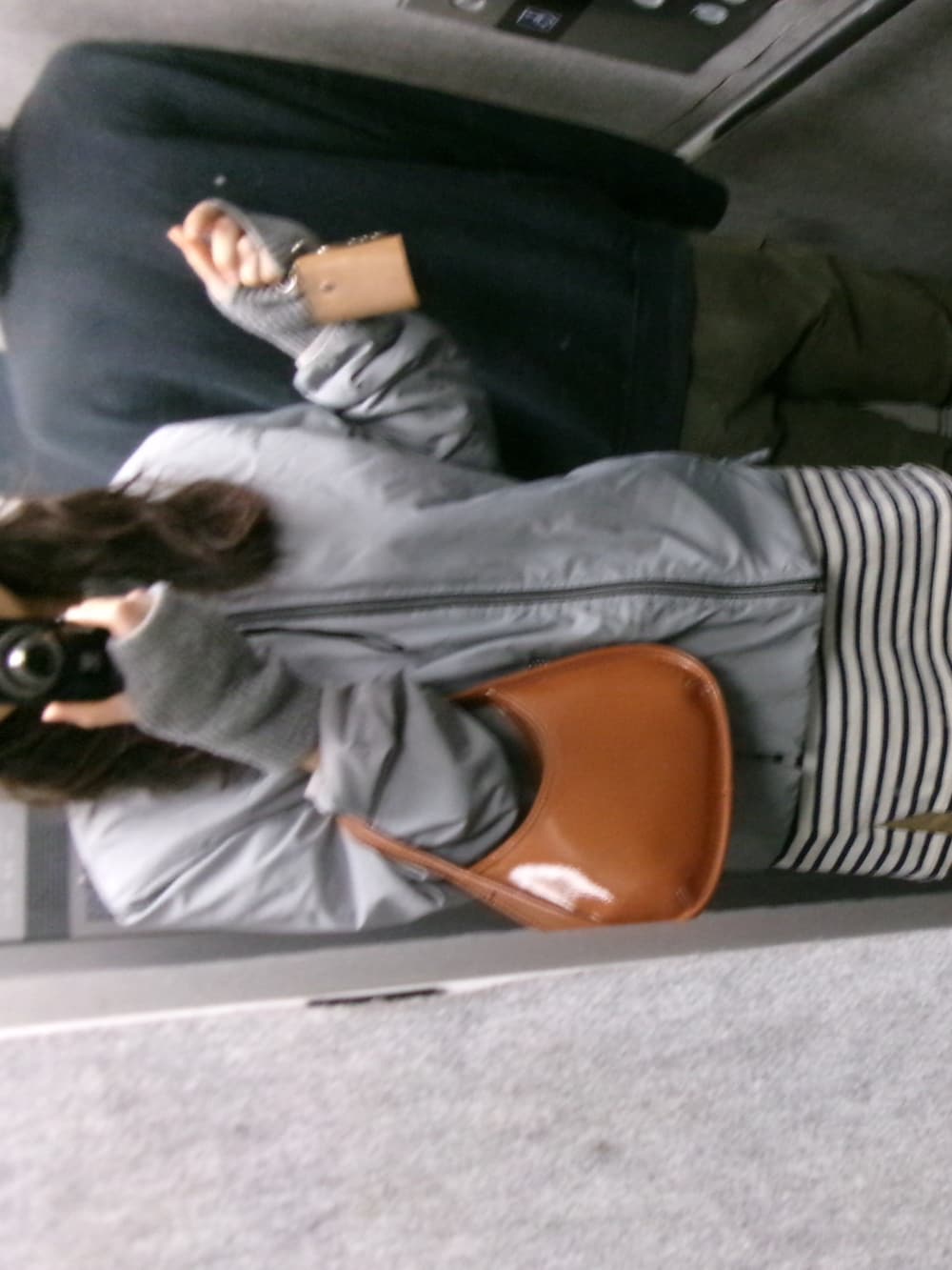 ブラウン系のハンドバッグ、ブラウン系のモカシン/デッキシューズ、グレー系のナイロンジャケットを着用したレディースの冬コーディネートの2枚目の写真