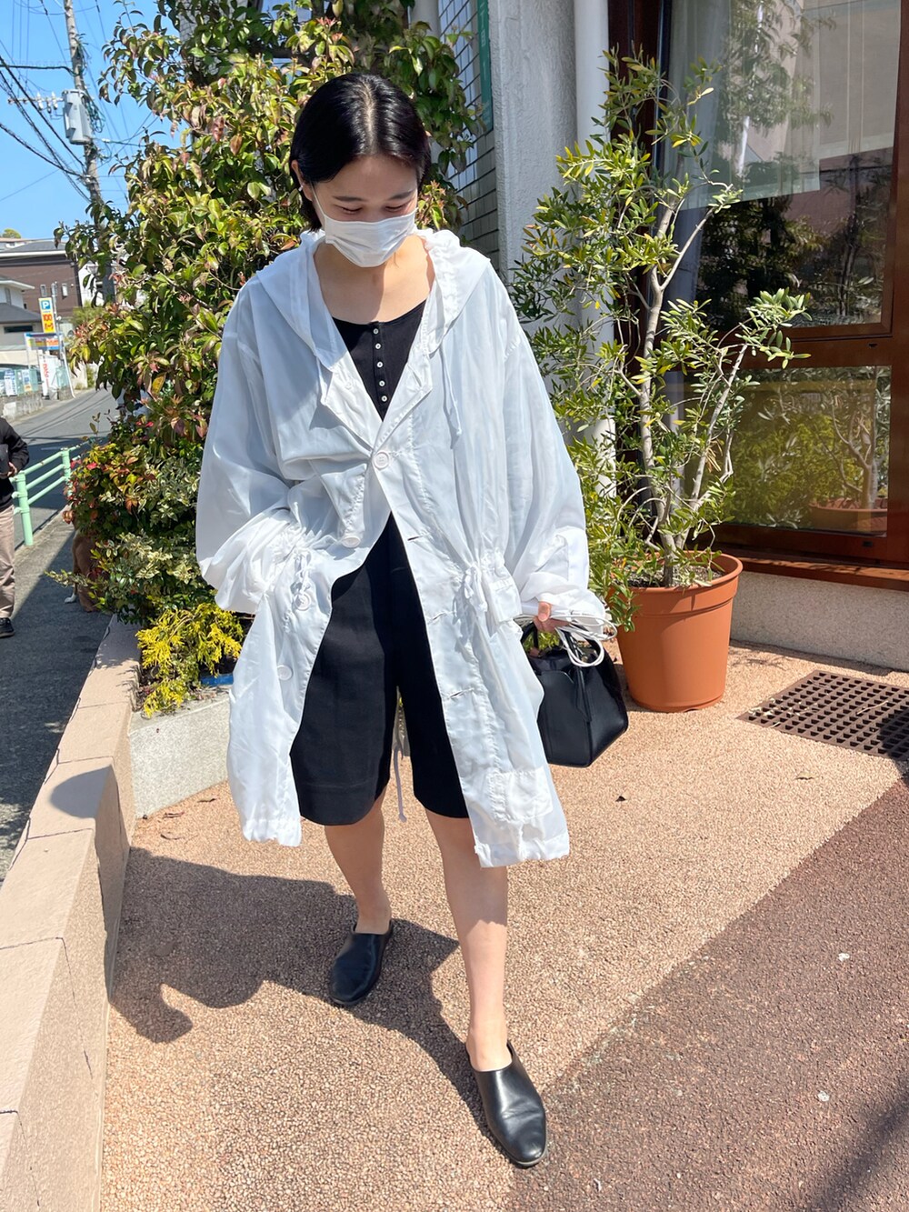 ホワイト系のジャケット/アウター、ブラック系のハンドバッグ、ブラック系のパンツを着用したレディースの春コーディネートの2枚目の写真