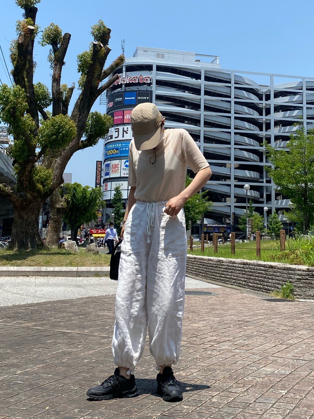 ホワイト系のパンツ、ブラック系のスニーカー、ブラック系のハンドバッグを着用したレディースの夏コーディネートの3枚目の写真