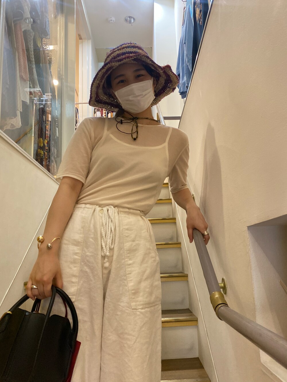 ブラック系のハンドバッグ、ベージュ系のキャップ、グリーン系のその他を着用したレディースの夏コーディネートの2枚目の写真