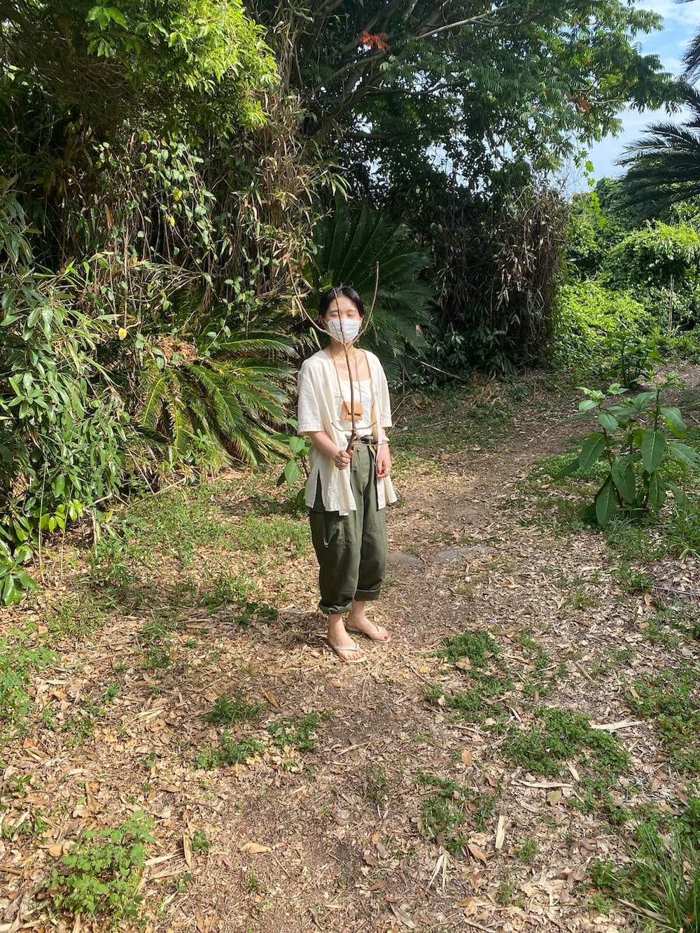 グリーン系のカーゴパンツ、ベージュ系のビーチサンダル、ベージュ系のシャツ/ブラウスを着用したレディースの春コーディネートの2枚目の写真