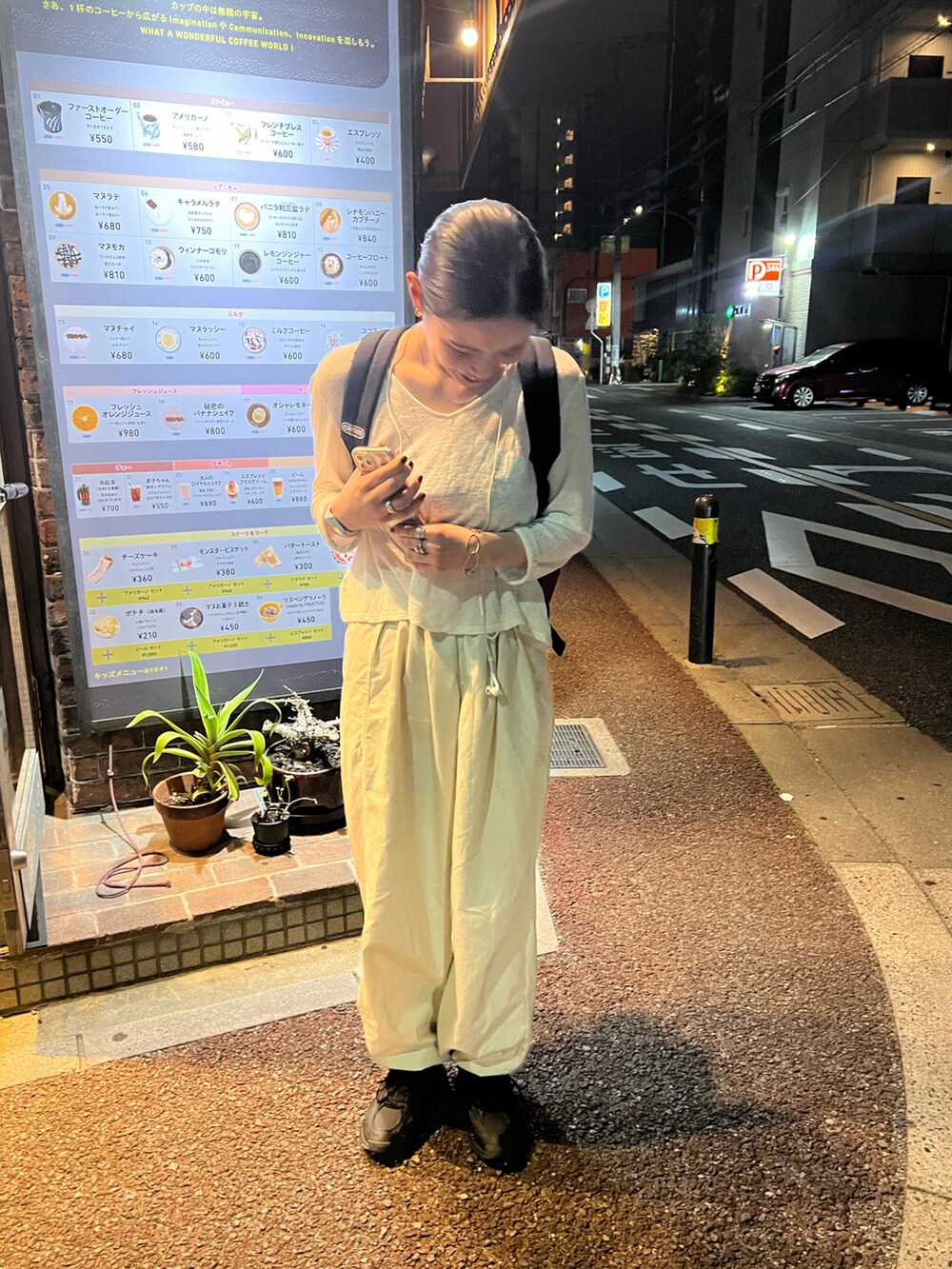 レッド系のバックパック/リュック、ブラック系のスニーカー、ベージュ系のパンツを着用したレディースの春コーディネートの3枚目の写真