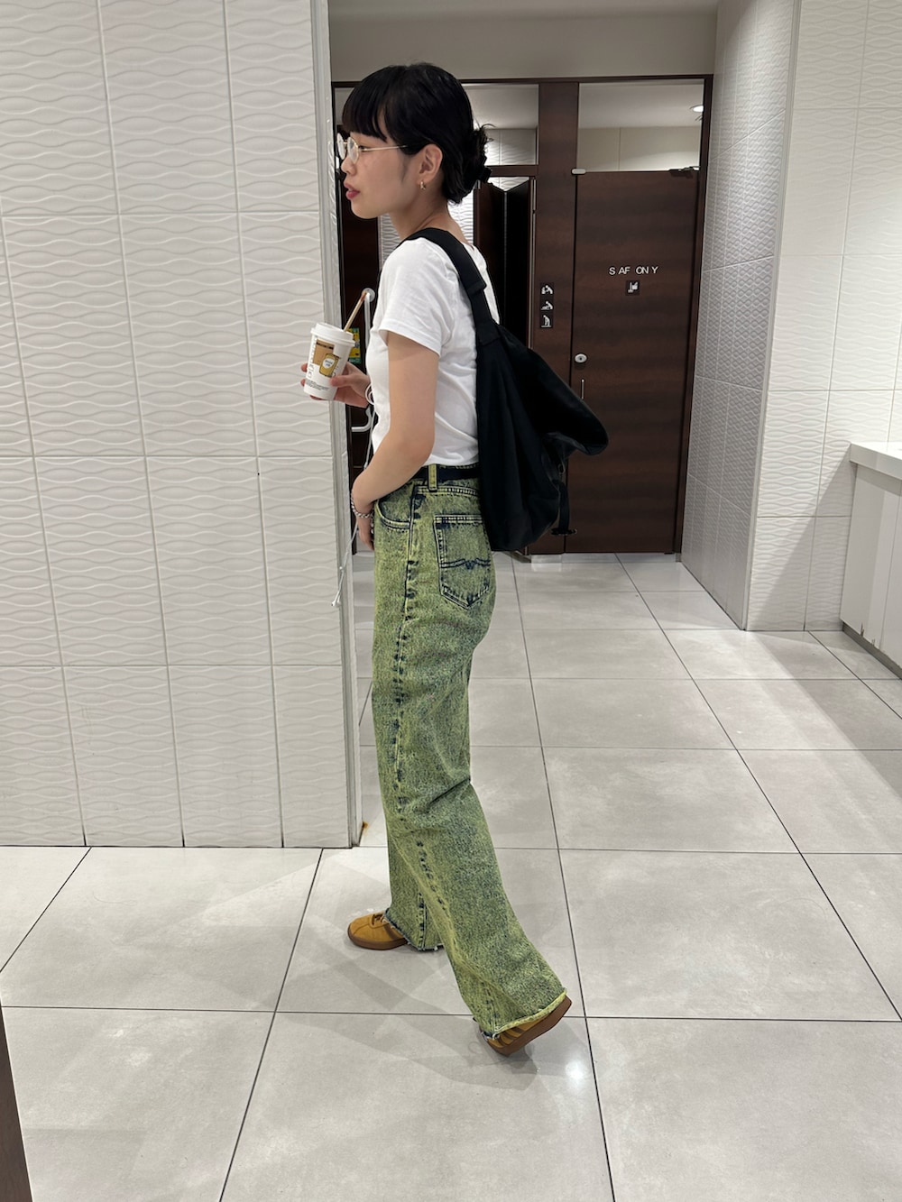 イエロー系のデニムパンツ、ブラウン系のスニーカー、ブラック系のメッセンジャーバッグを着用したレディースの秋コーディネートの2枚目の写真