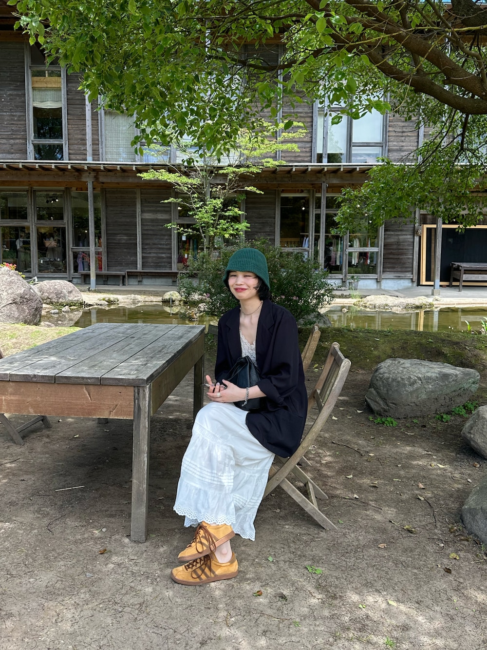 ブラウン系のスニーカー、グリーン系のキャップを着用したレディースの春コーディネートの2枚目の写真