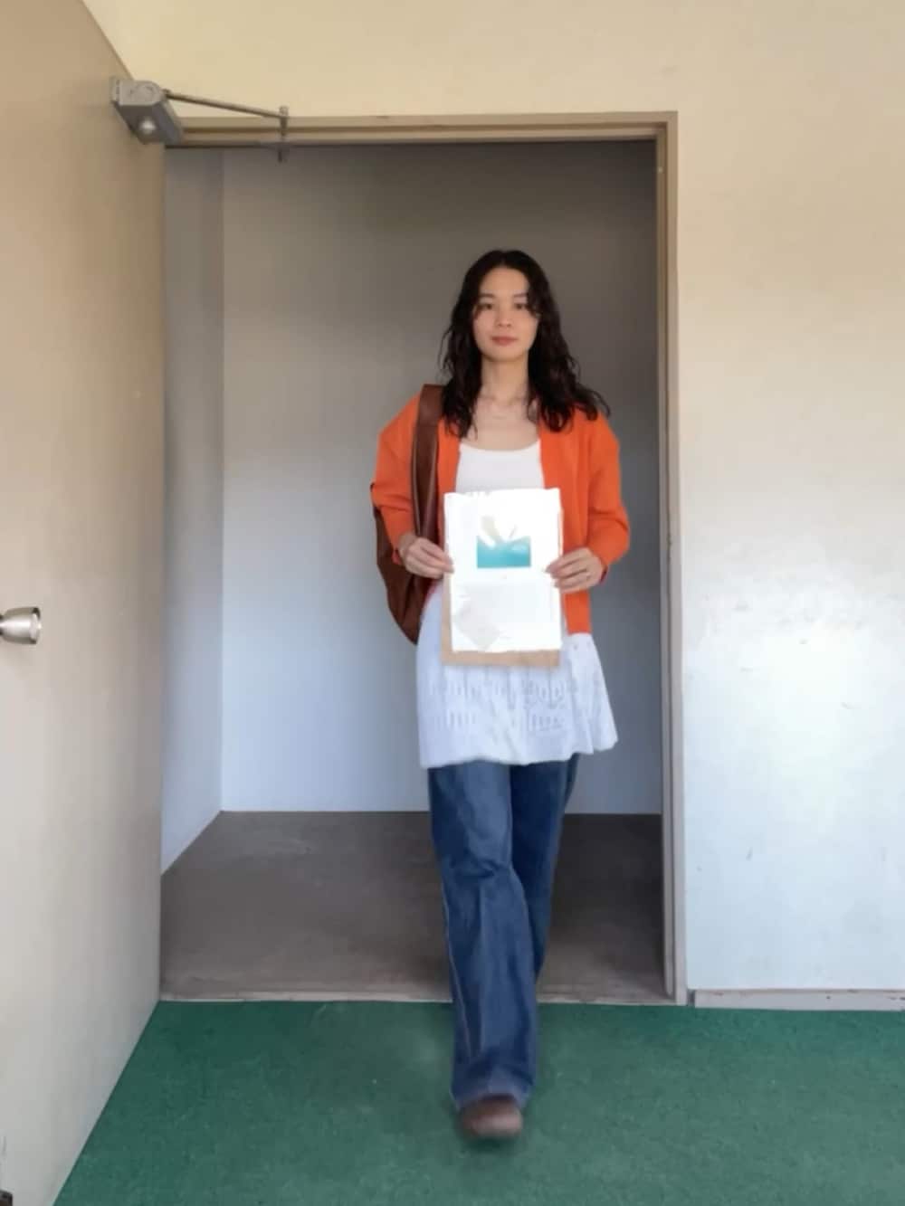 オレンジ系のカーディガン/ボレロを着用したレディースの秋コーディネートの2枚目の写真