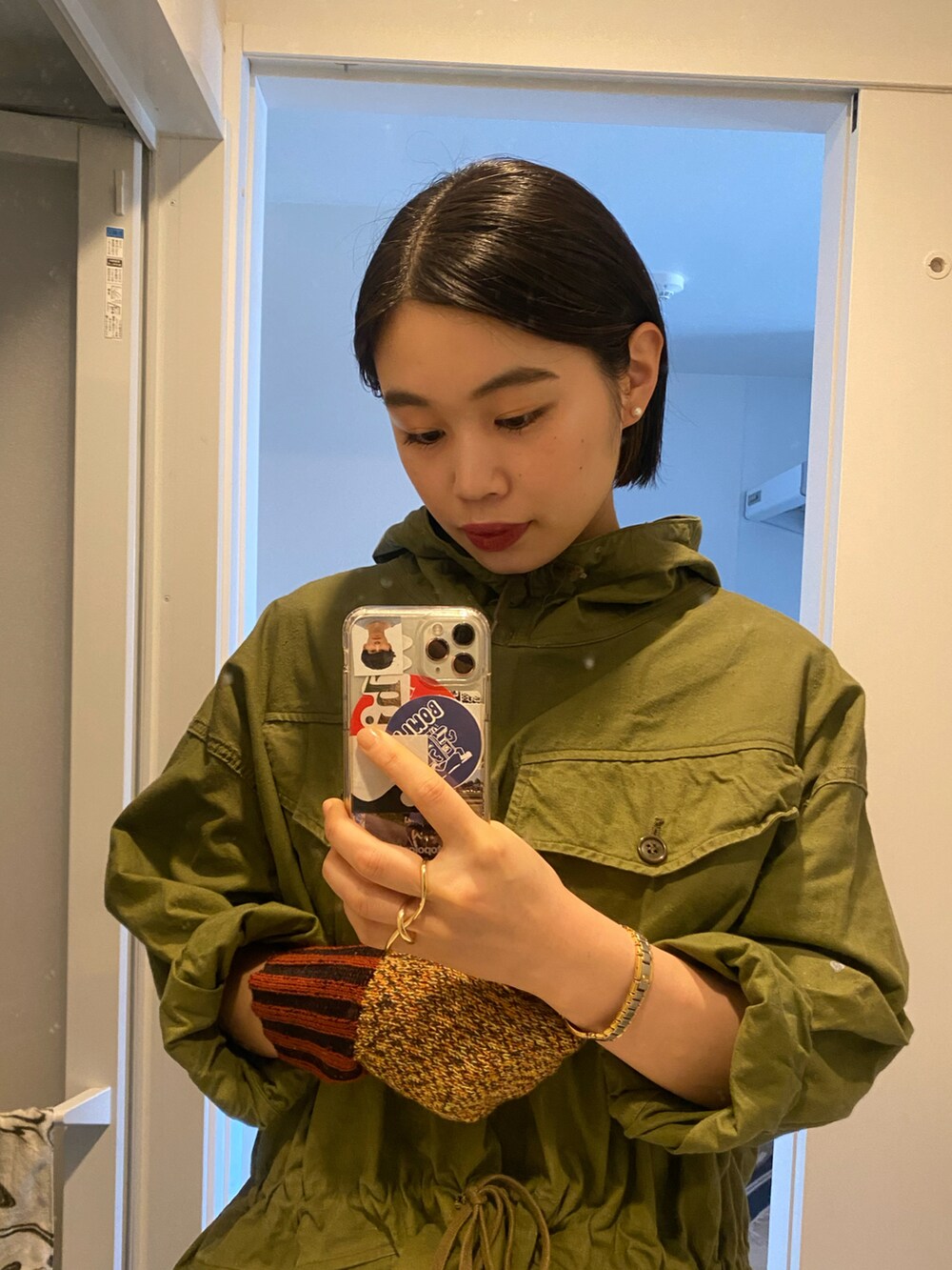 グリーン系のミリタリージャケット、レッド系のスカート、ブラック系のスニーカーを着用したレディースの冬コーディネートの5枚目の写真