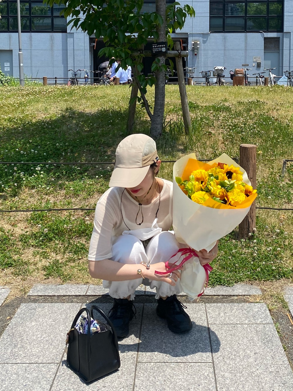 ホワイト系のパンツ、ブラック系のスニーカー、ブラック系のハンドバッグを着用したレディースの夏コーディネートの2枚目の写真