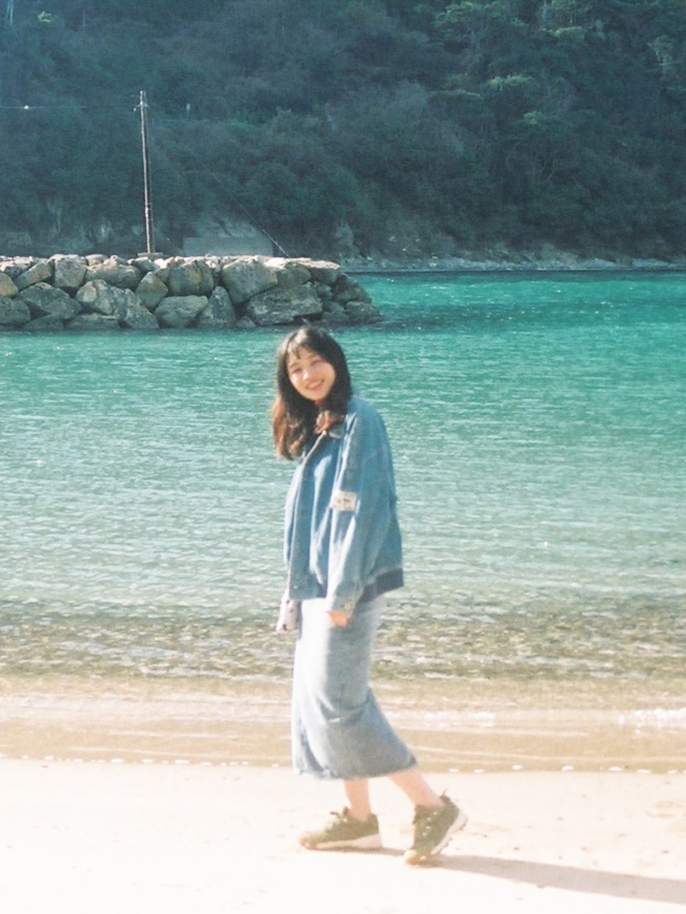 グリーン系のスニーカー、ブルー系のデニムスカート、ブルー系のデニムジャケットを着用したレディースの冬コーディネートの2枚目の写真