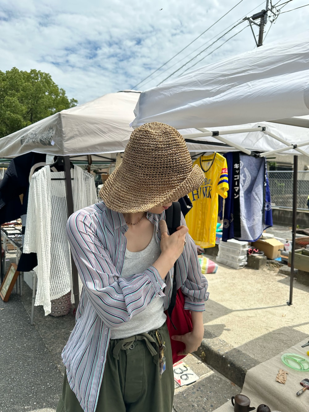 レッド系のバックパック/リュック、グリーン系のカーゴパンツ、ブラック系のサンダルを着用したレディースの夏コーディネートの2枚目の写真