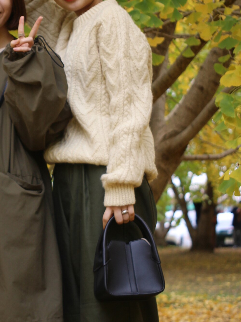 グリーン系のカーゴパンツ、ベージュ系のニット/セーター、ブラック系のハンドバッグを着用したレディースの秋コーディネートの3枚目の写真