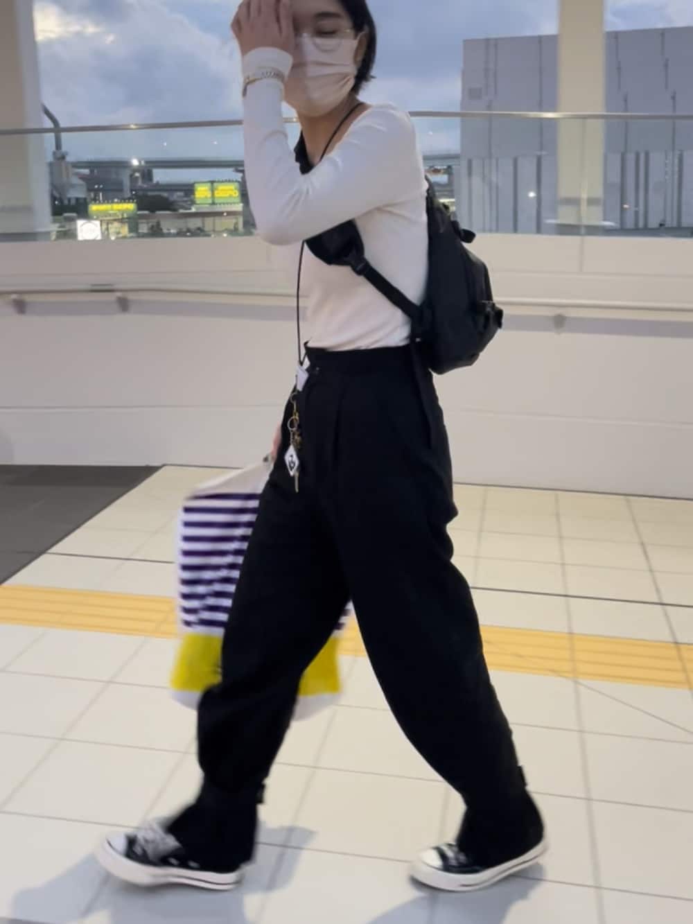 グレー系のトップス、ブラック系のパンツ、ブラック系のスニーカーを着用したレディースの秋コーディネートの4枚目の写真