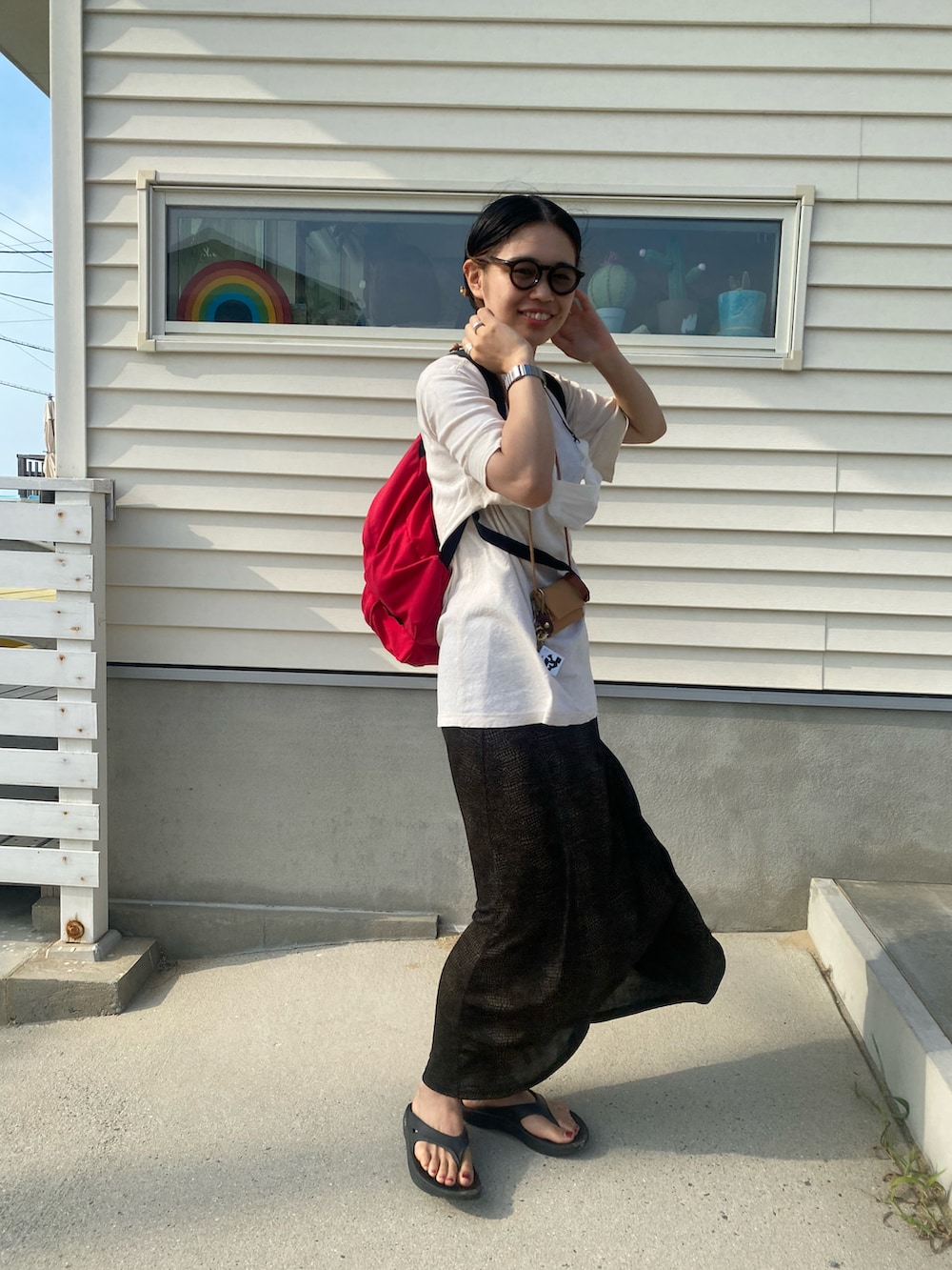 レッド系のバックパック/リュック、ブラック系のスカート、ブラック系のサンダルを着用したレディースの夏コーディネートの2枚目の写真