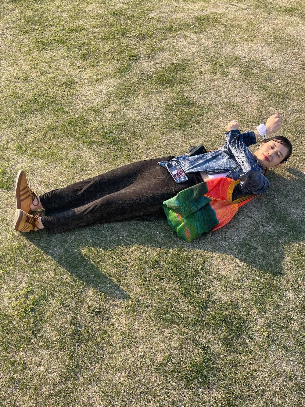 ブラウン系のスニーカー、ブラック系のスカート、ブルー系のパーカーを着用したレディースの春コーディネートの3枚目の写真