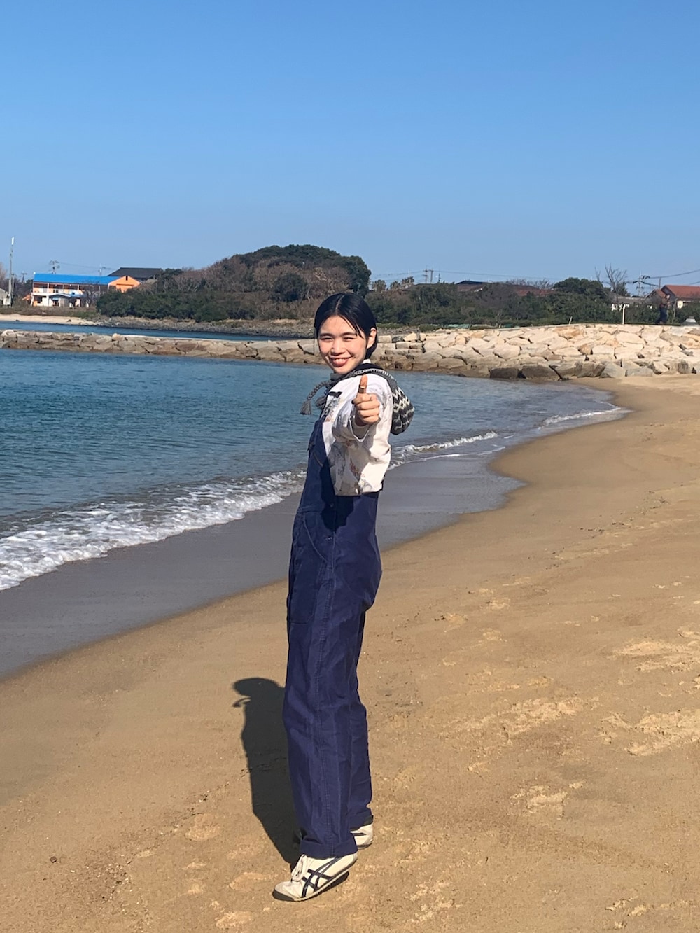 ブルー系のオールインワン・サロペット、グレー系のスニーカー、グレー系のニットキャップ/ビーニーを着用したレディースの冬コーディネートの2枚目の写真