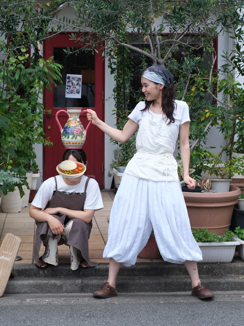 ブラウン系のサンダル、ホワイト系のエプロンを着用したレディースの夏コーディネートの2枚目の写真