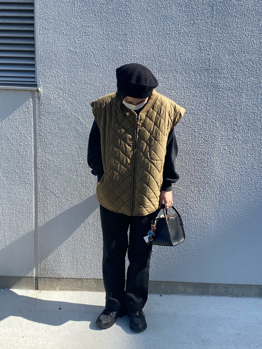 ベージュ系のダウンベスト、ブラック系のその他パンツ、ブラック系のハンドバッグを着用したレディースの秋コーディネートの3枚目の写真