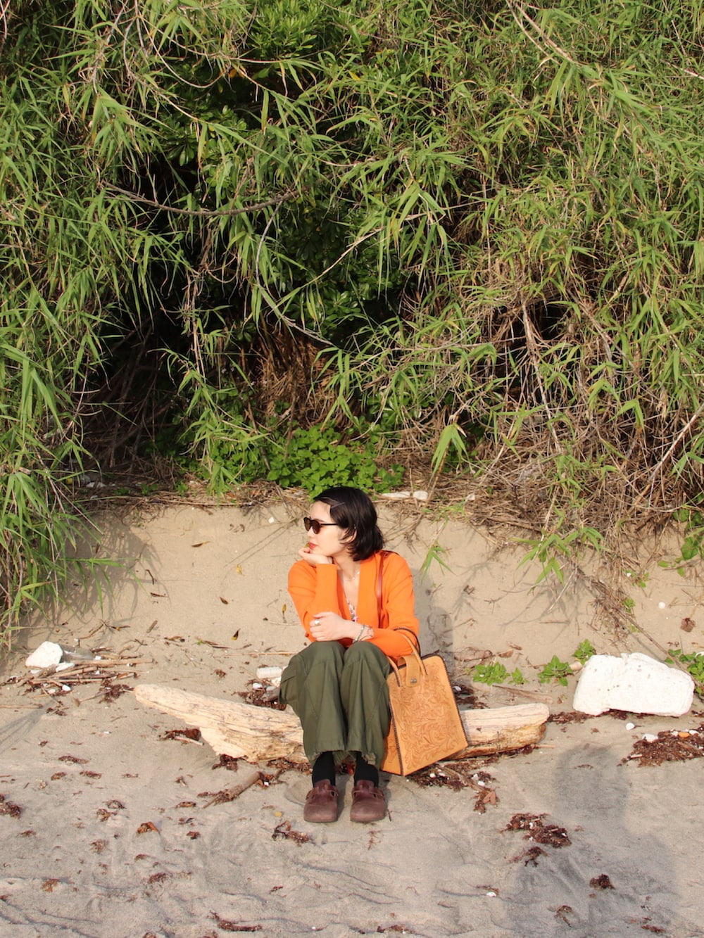 オレンジ系のカーディガン/ボレロ、ブラウン系のトートバッグ、グリーン系のカーゴパンツを着用したレディースの春コーディネートの2枚目の写真