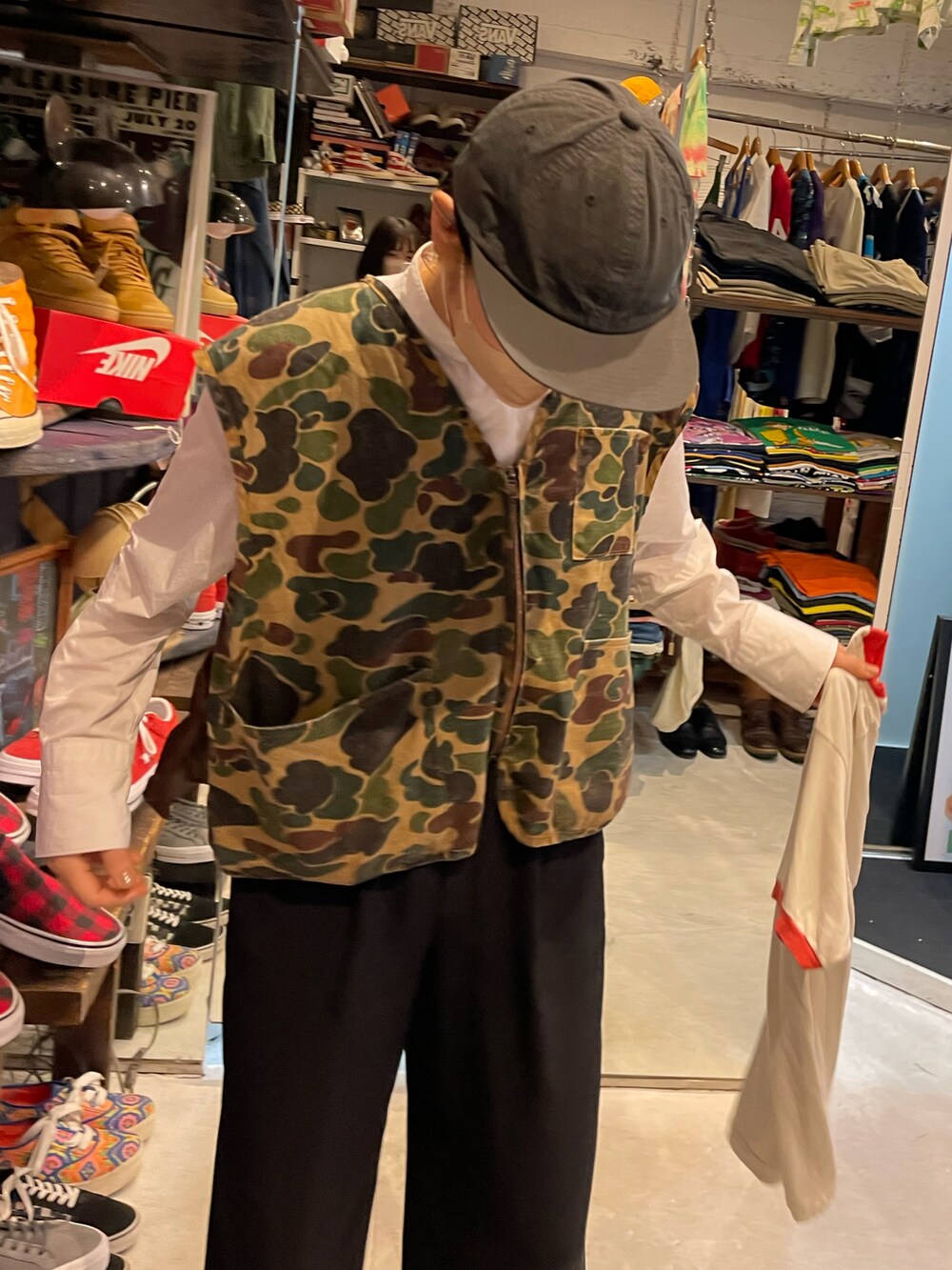 グリーン系のベスト、ブラック系のスニーカー、グリーン系のキャップを着用したレディースの春コーディネートの2枚目の写真