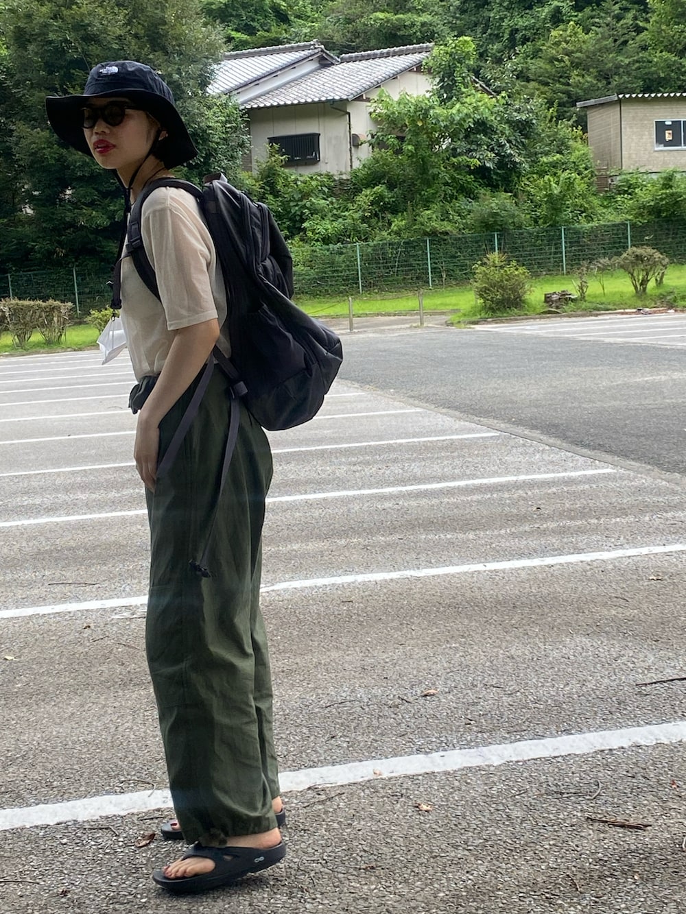 グリーン系のカーゴパンツ、ブラック系のサンダル、グレー系のバックパック/リュックを着用したレディースの夏コーディネートの2枚目の写真