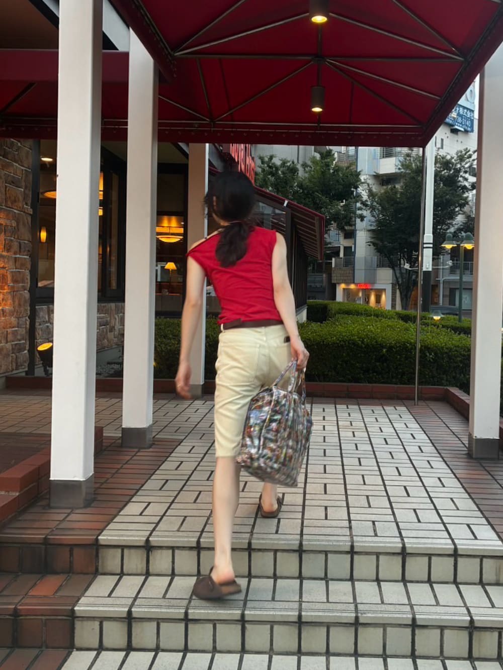 レッド系のタンクトップ、イエロー系のパンツを着用したレディースの夏コーディネートの2枚目の写真