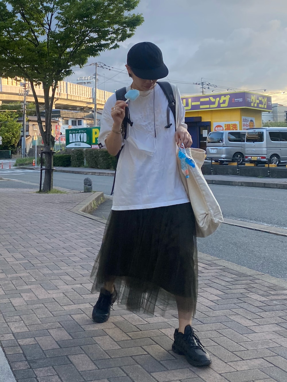 グリーン系のスカート、ホワイト系のトップス、ベージュ系のトートバッグを着用したレディースの夏コーディネートの2枚目の写真