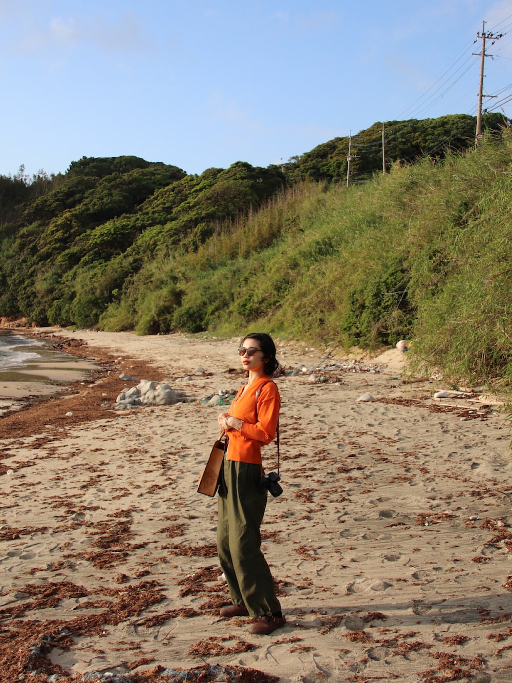 オレンジ系のカーディガン/ボレロ、ブラウン系のトートバッグ、グリーン系のカーゴパンツを着用したレディースの春コーディネートの3枚目の写真