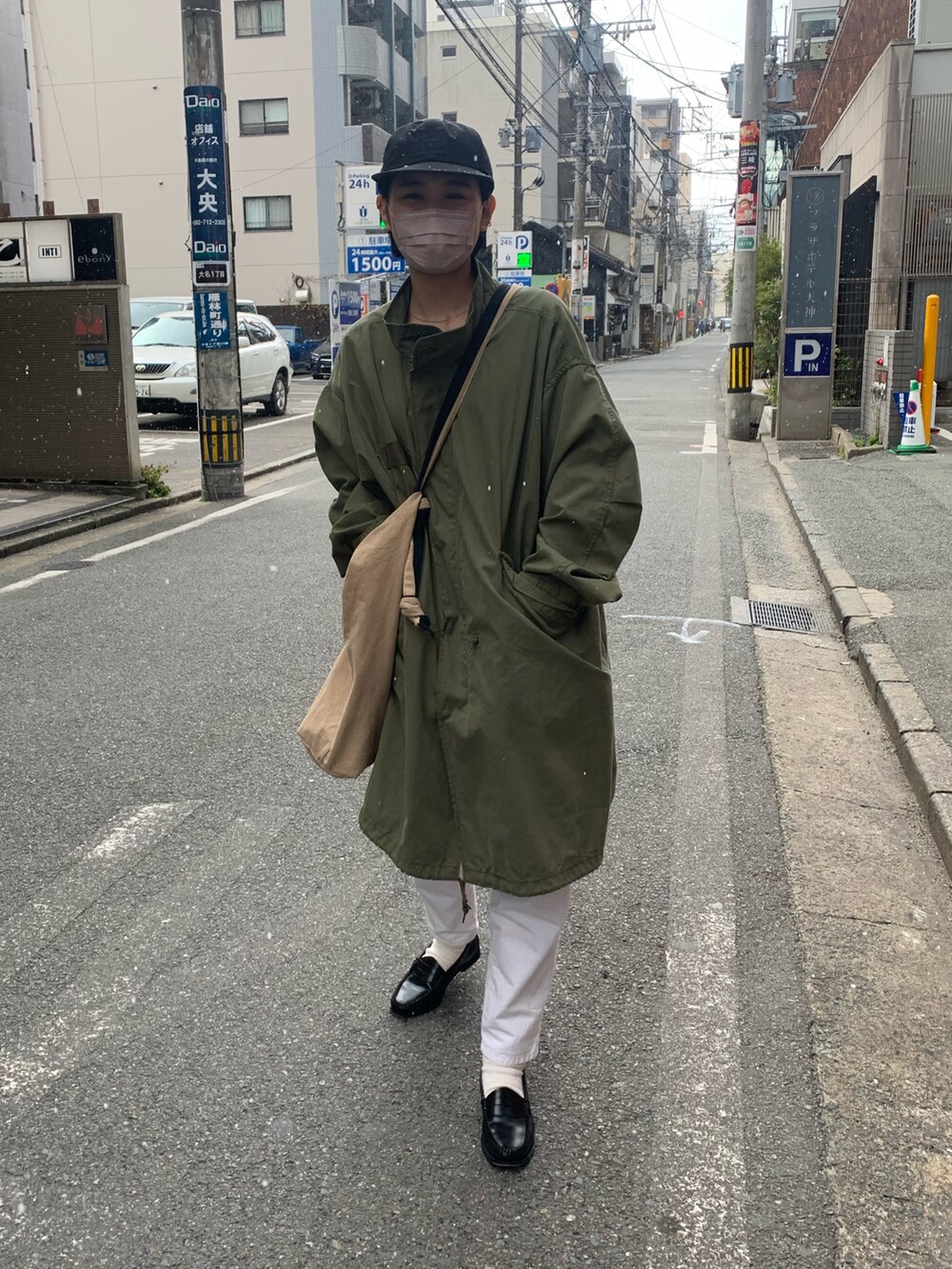 グリーン系のモッズコート、ベージュ系のショルダーバッグ、ホワイト系のパンツを着用したレディースの冬コーディネートの2枚目の写真