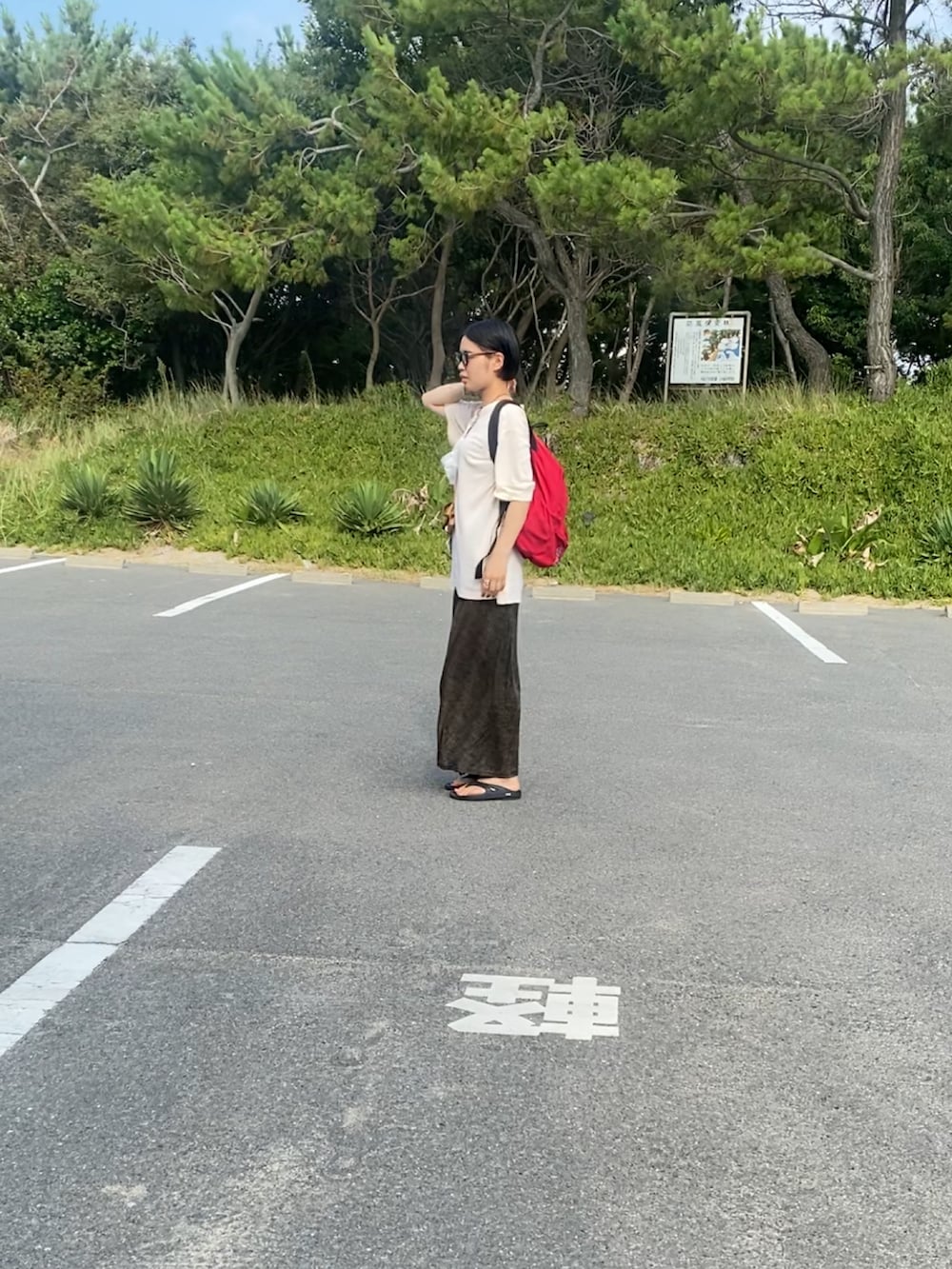 レッド系のバックパック/リュック、ブラック系のスカート、ブラック系のサンダルを着用したレディースの夏コーディネートの3枚目の写真