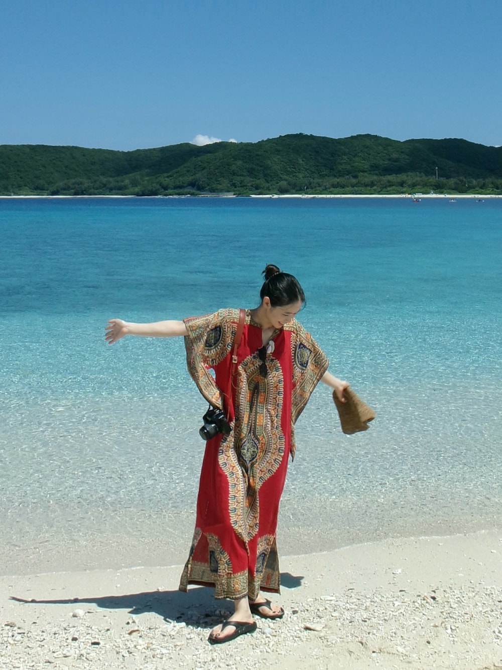 レッド系のワンピース、ブラック系のサンダルを着用したレディースの夏コーディネートの2枚目の写真