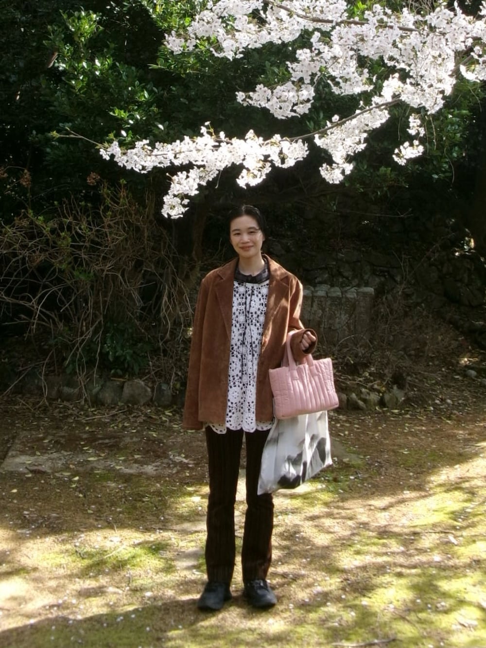 ブラウン系のテーラードジャケット、ブラック系のスニーカー、ブラウン系のパンツを着用したレディースの春コーディネートの2枚目の写真