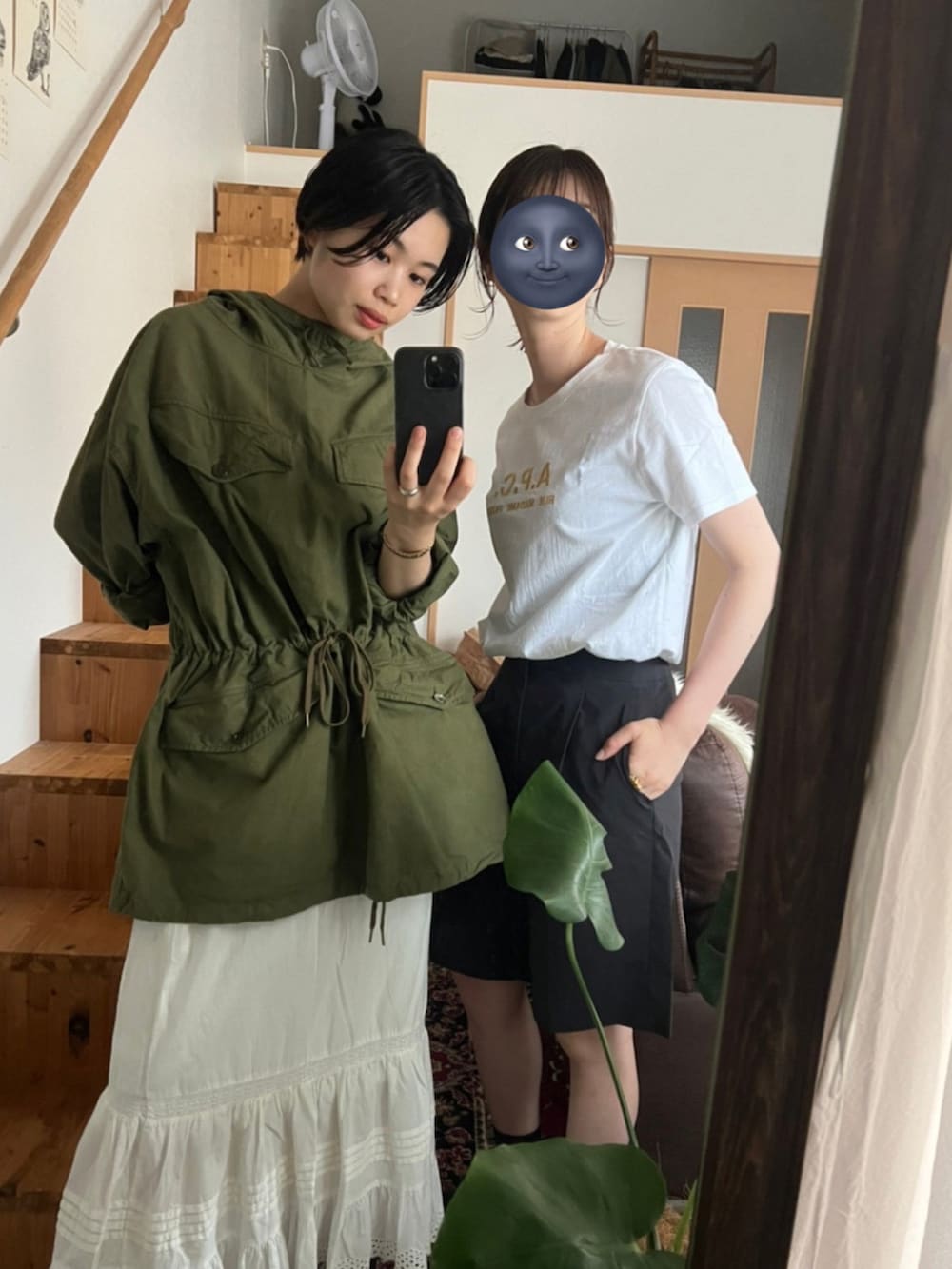 グリーン系のミリタリージャケット、ホワイト系のスカート、ブラック系のスニーカーを着用したレディースの夏コーディネートの2枚目の写真