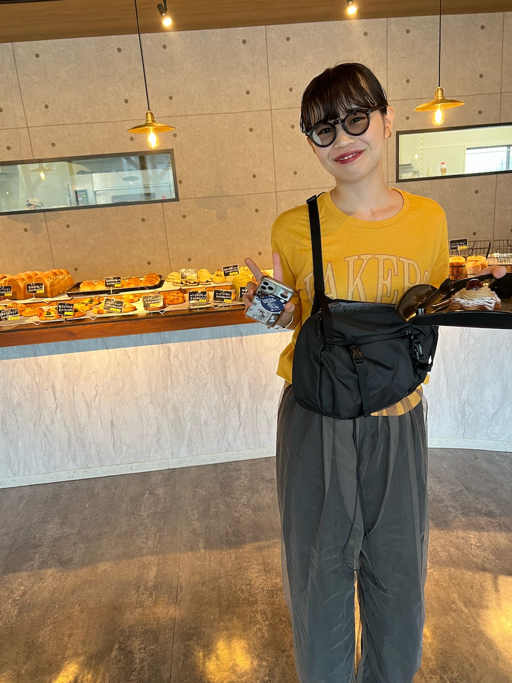 グリーン系のパンツ、イエロー系のTシャツ/カットソー、ブラック系のショルダーバッグを着用したレディースの夏コーディネートの2枚目の写真
