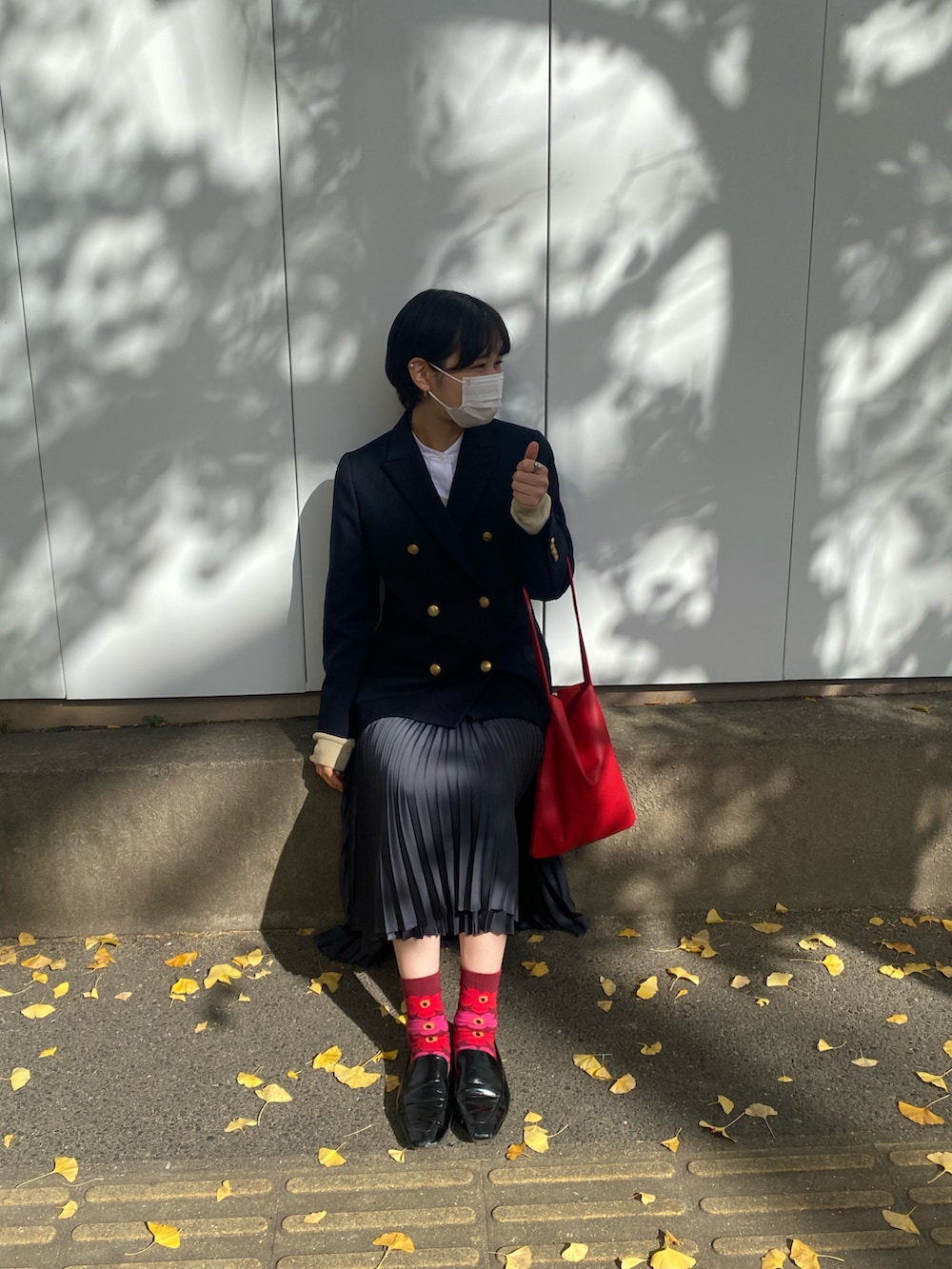 レッド系のトートバッグ、グレー系のスカート、ブルー系のテーラードジャケットを着用したレディースの秋コーディネートの2枚目の写真