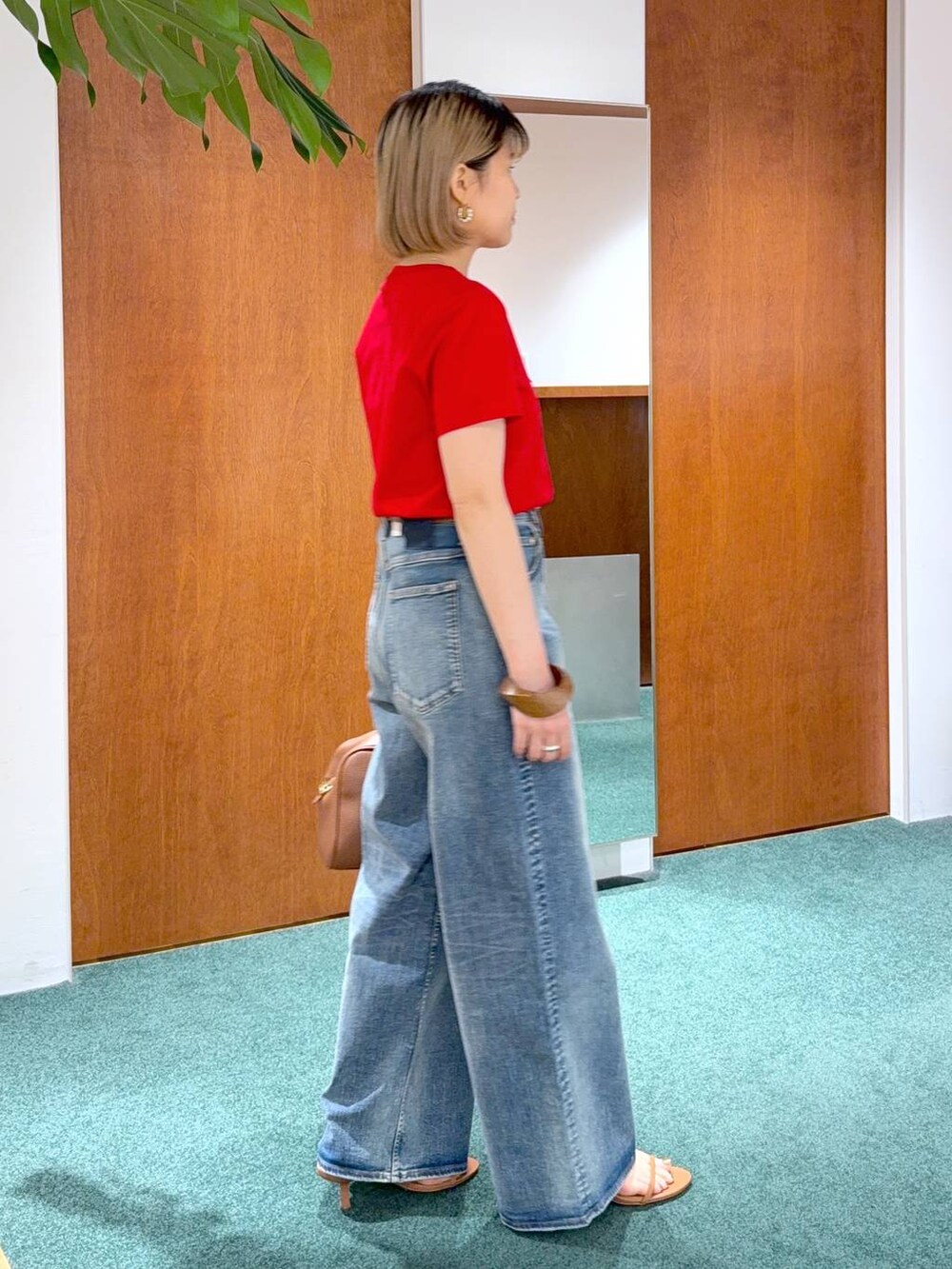 ブルー系のデニムパンツ、レッド系のTシャツ/カットソー、ブラウン系のボストンバッグを着用したレディースの春コーディネートの2枚目の写真