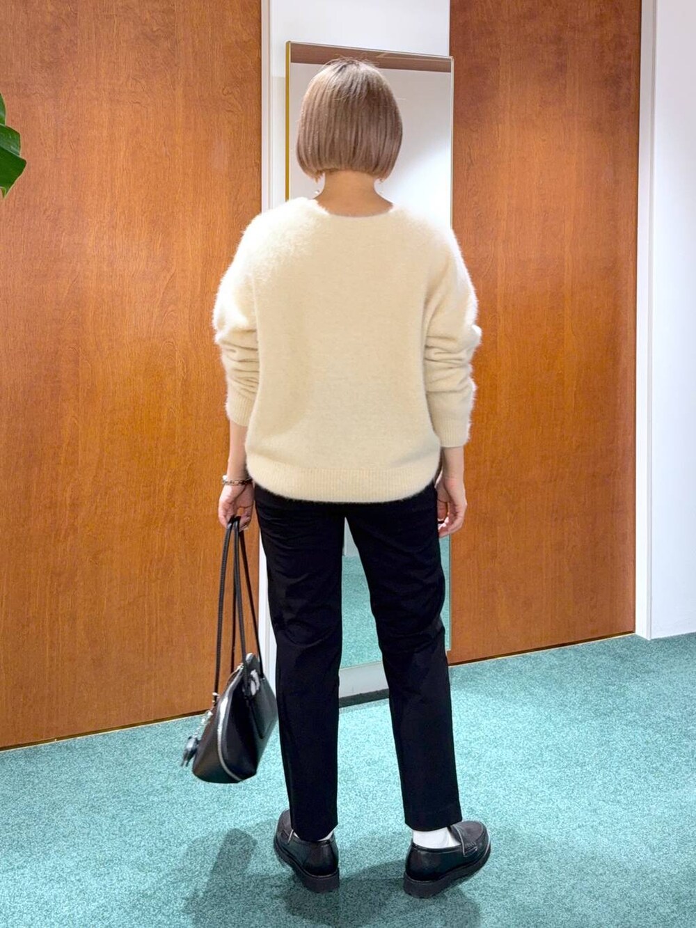 ブラック系のトートバッグ、ベージュ系のニット/セーター、ブラック系のローファーを着用したレディースの冬コーディネートの3枚目の写真