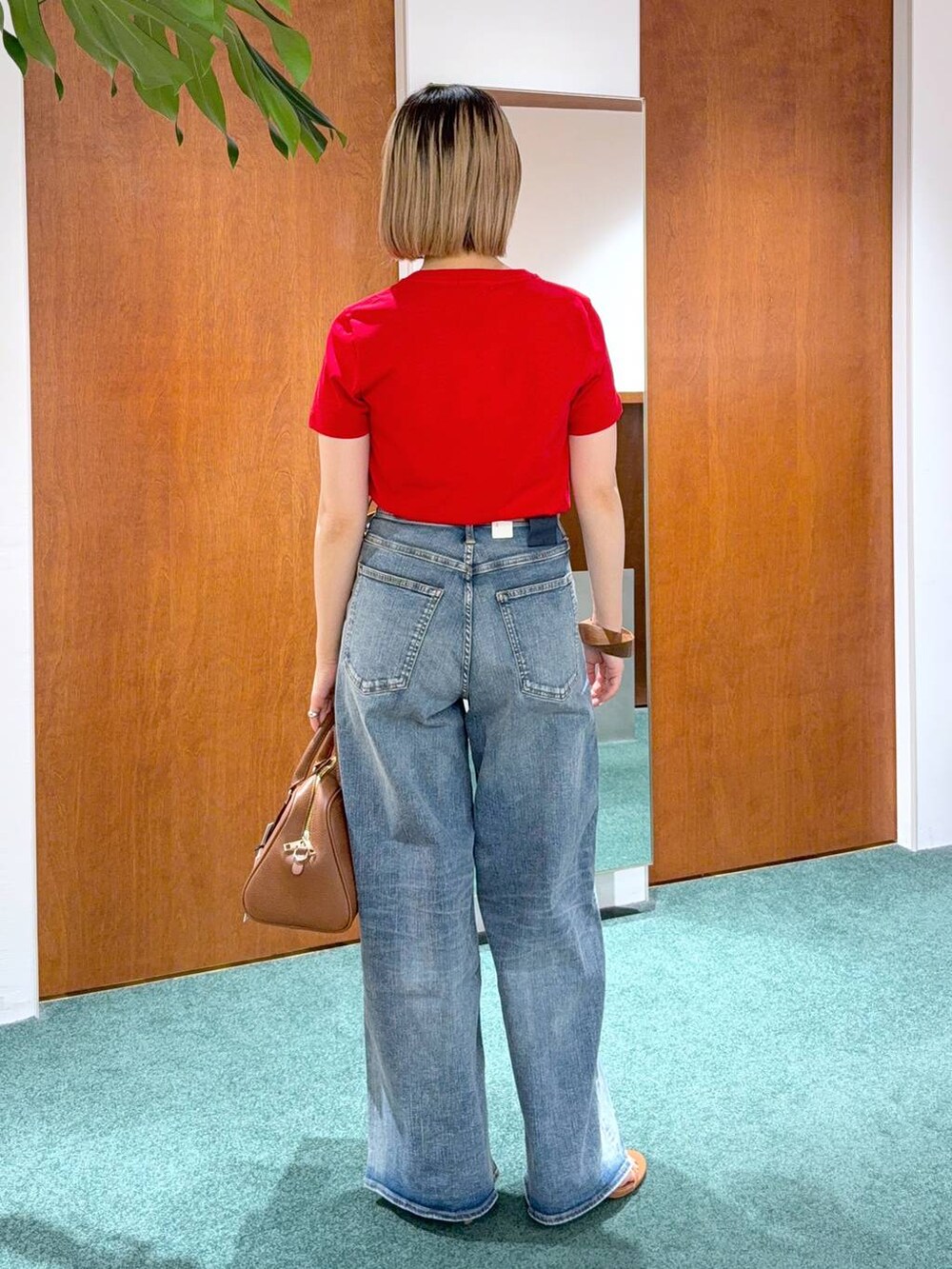 ブルー系のデニムパンツ、レッド系のTシャツ/カットソー、ブラウン系のボストンバッグを着用したレディースの春コーディネートの3枚目の写真
