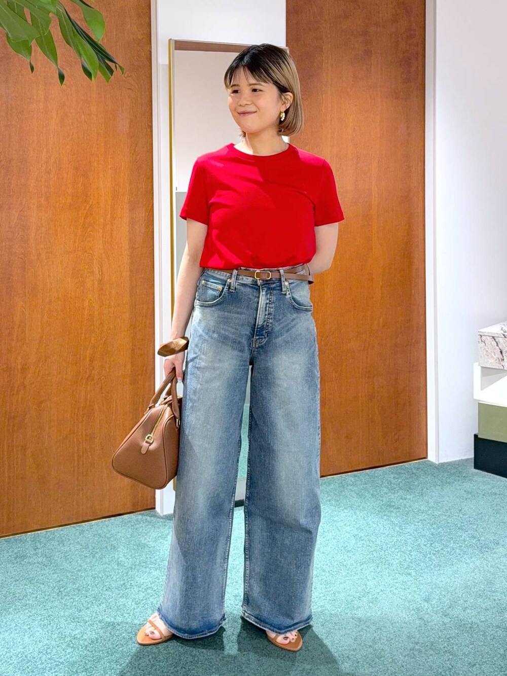 ブルー系のデニムパンツ、レッド系のTシャツ/カットソー、ブラウン系のボストンバッグを着用したレディースの春コーディネートの4枚目の写真