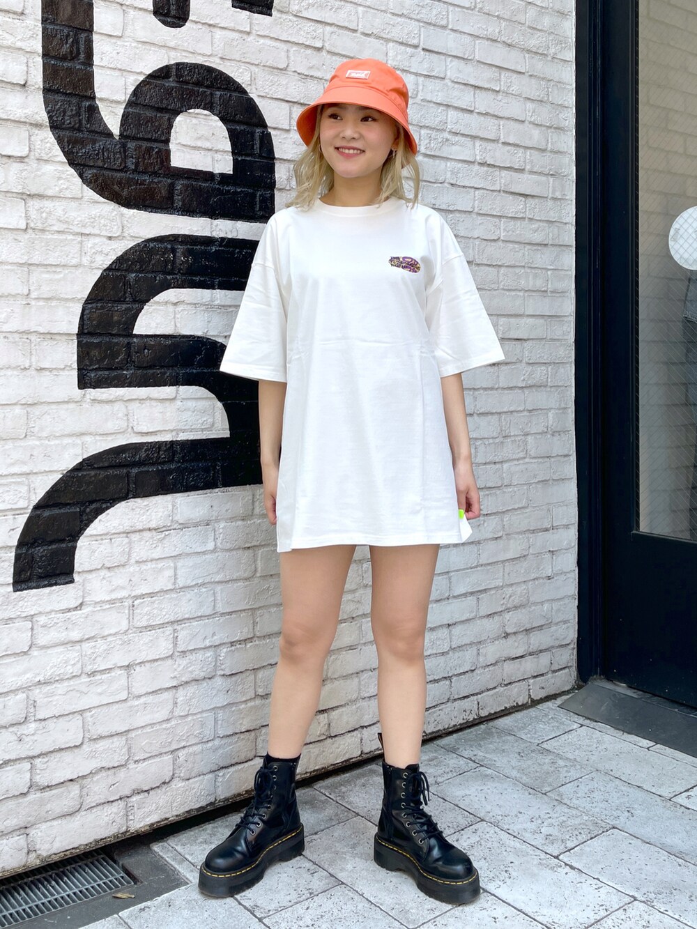 オレンジ系のTシャツ/カットソー、オレンジ系のハットを着用したレディースの夏コーディネートの2枚目の写真