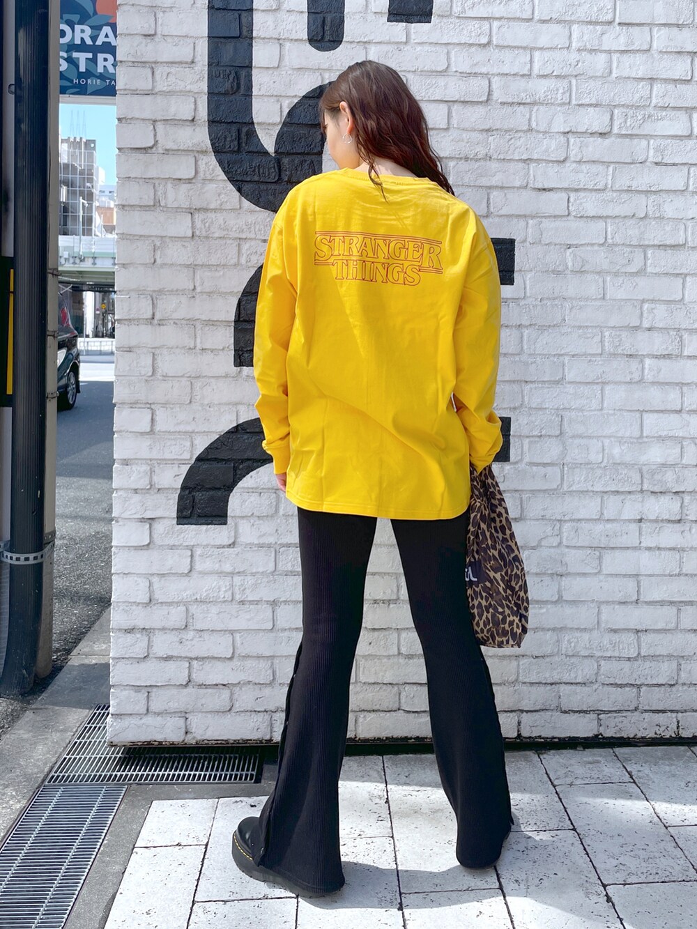 イエロー系のTシャツ/カットソー、ブラック系のその他パンツ、ベージュ系のエコバッグ/サブバッグを着用したレディースの春コーディネートの2枚目の写真