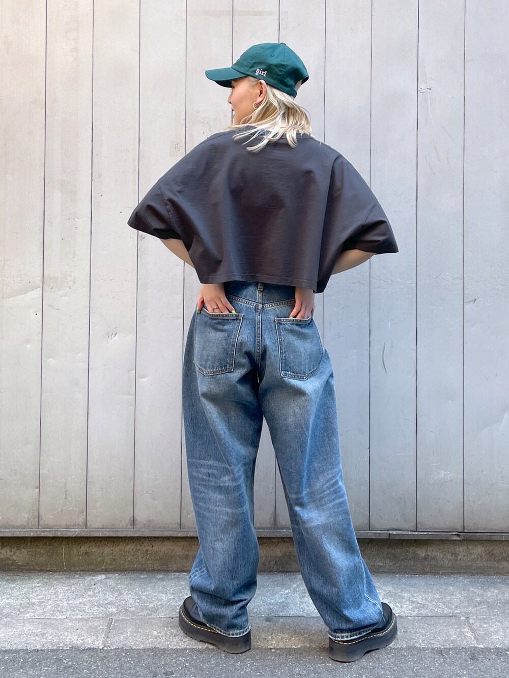 グレー系のTシャツ/カットソー、ブルー系のデニムパンツ、グリーン系のキャップを着用したレディースの春コーディネートの2枚目の写真