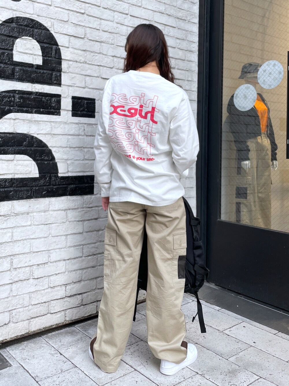 ホワイト系のTシャツ/カットソー、ベージュ系のその他パンツ、ブラック系のバックパック/リュックを着用したレディースの春コーディネートの2枚目の写真