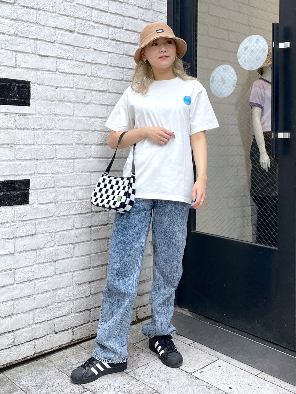 ホワイト系のTシャツ/カットソー、ブルー系のデニムパンツ、ホワイト系のハンドバッグを着用したレディースの夏コーディネートの2枚目の写真