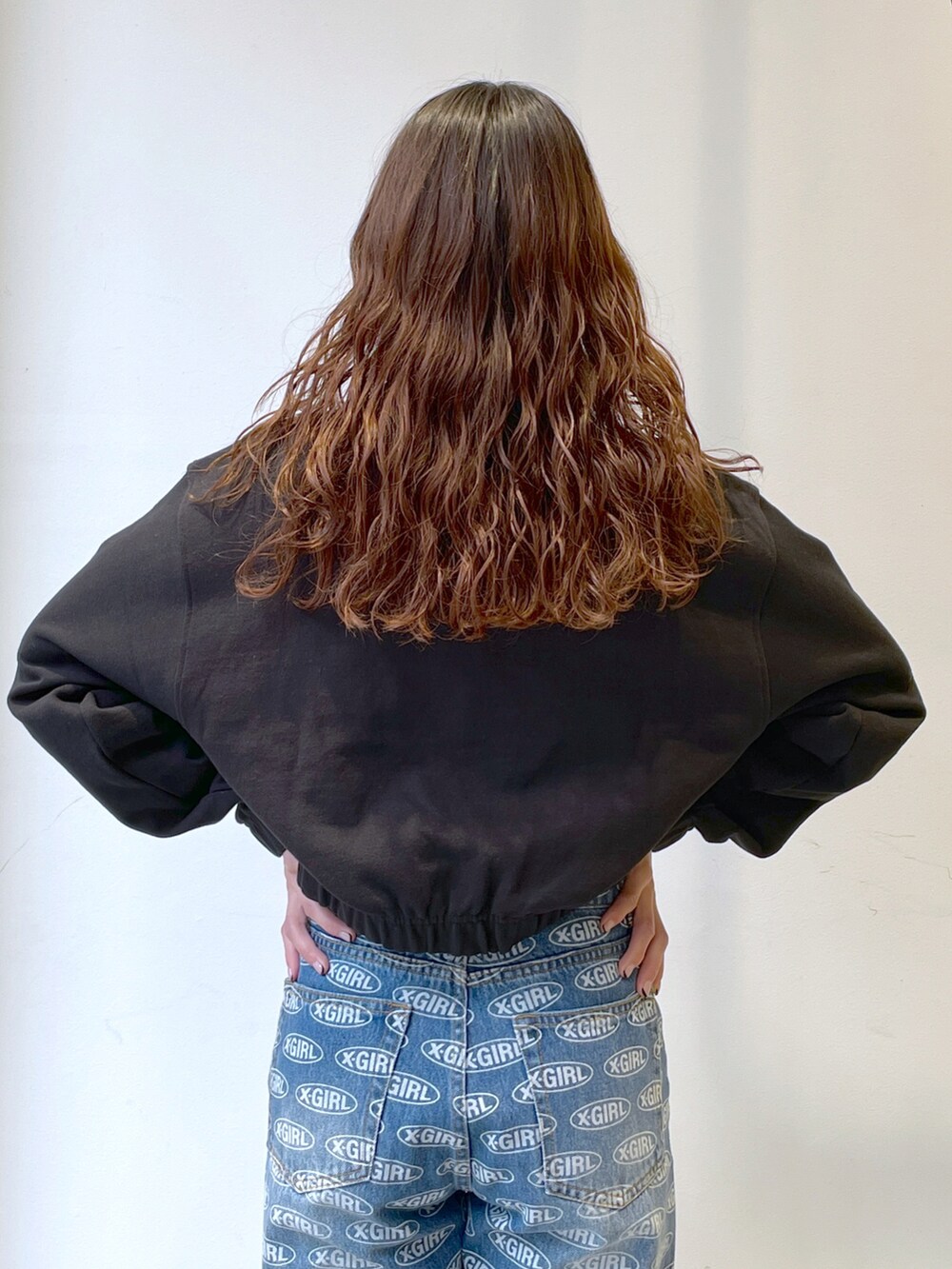 ブラック系のスウェット、ブルー系のデニムパンツ、ホワイト系のトートバッグを着用したレディースの春コーディネートの4枚目の写真